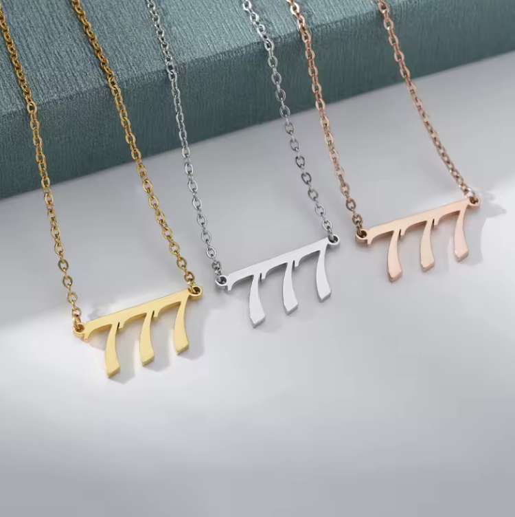Three angel number 777 necklaces displayed on a soft surface, available in gold, silver, and rose gold finishes. Each necklace features a sleek, modern pendant with a delicate chain, symbolizing luck, spiritual alignment, and divine guidance. The polished metal tones reflect light, highlighting their elegant and meaningful design.