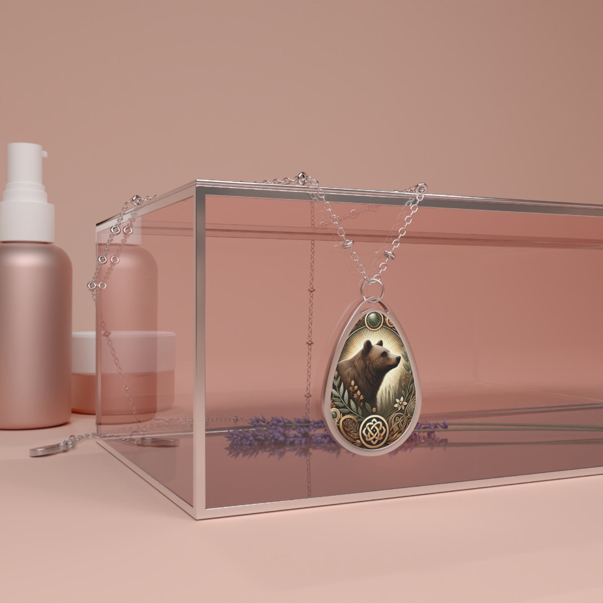 A silver bear pendant necklace draped over a modern, transparent jewelry box with a soft pink background. The pendant has an intricate design with nature-inspired details, complemented by minimalistic beauty product containers and sprigs of lavender in the scene.