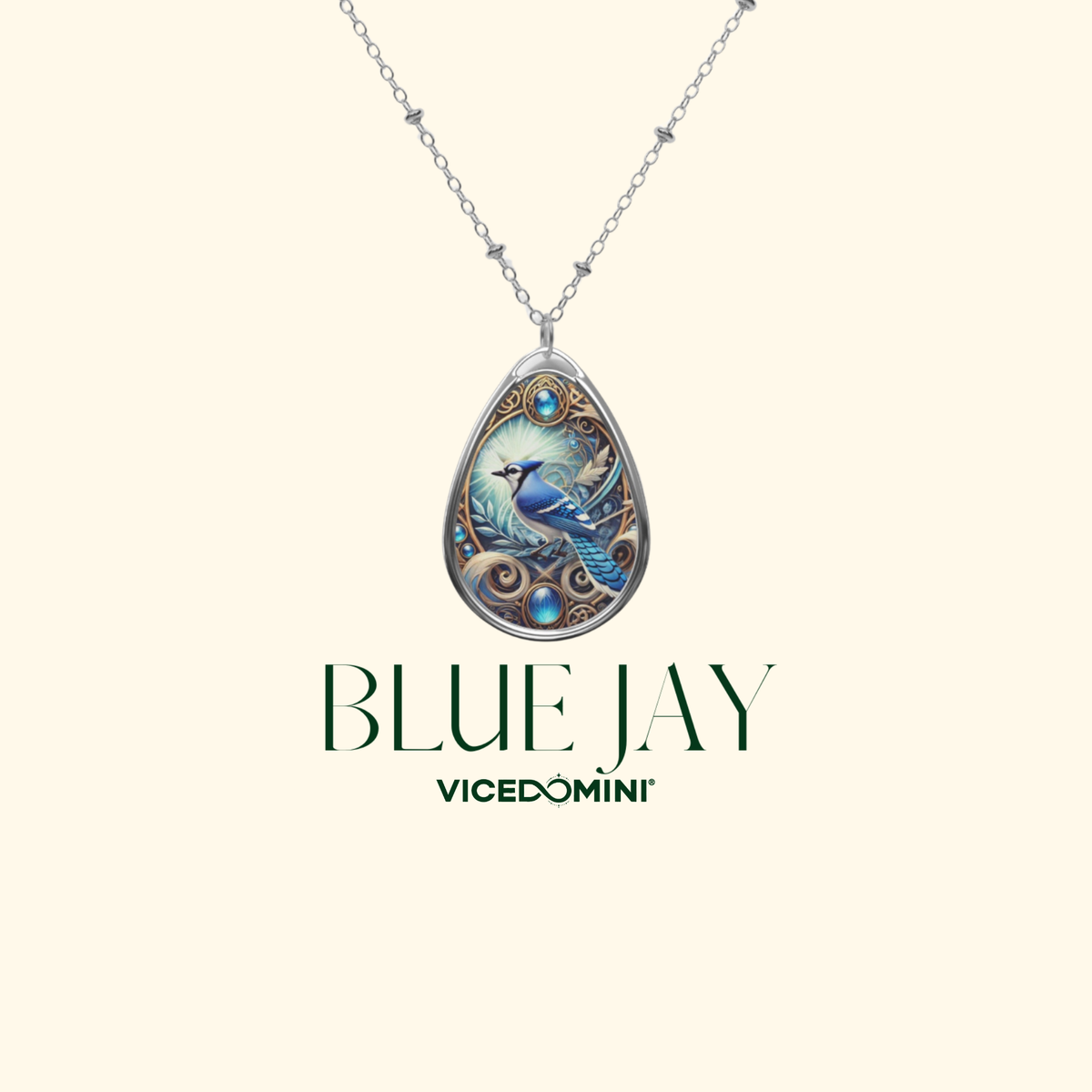 A teardrop-shaped pendant necklace featuring an intricate illustration of a blue bird on a silver-toned chain, set against a cream background with the text 'BLUE JAY' and 'VICEDOMINI' below.