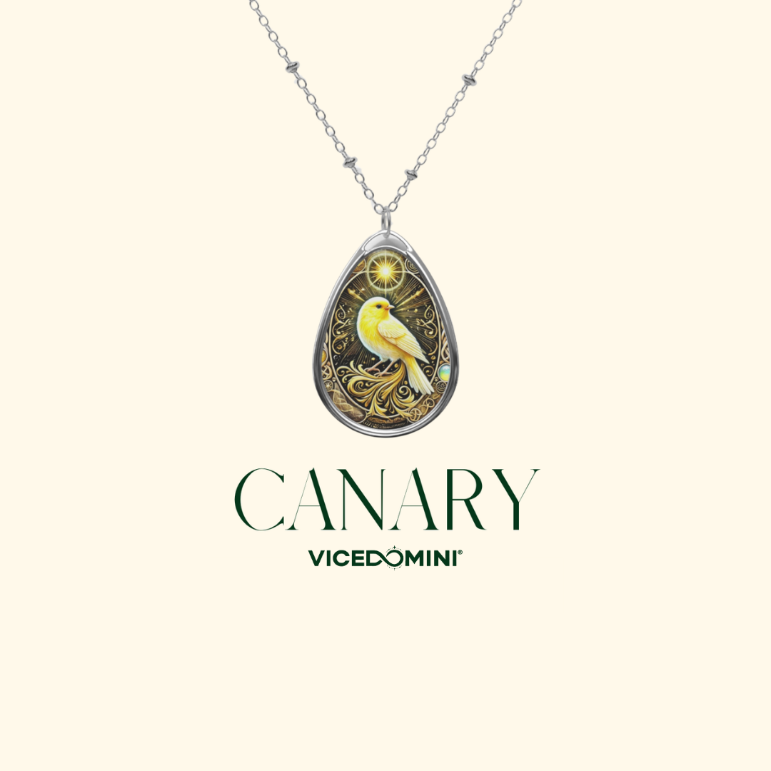 A teardrop-shaped pendant necklace featuring a yellow canary bird on an ornate gold patterned background, suspended from a silver chain. The brand name 'VICEDOMINI' and the word 'CANARY' are printed below the pendant on a light cream background.