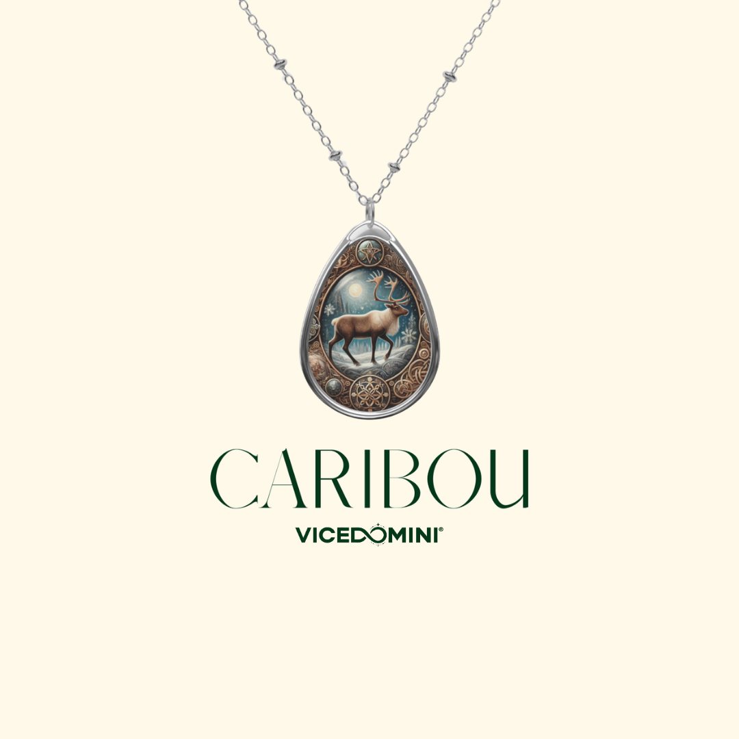 A silver teardrop pendant necklace featuring an engraved caribou deer design, displayed against a light cream background with the brand name 'VICEDOMINI' and 'CARIBOU' printed below.