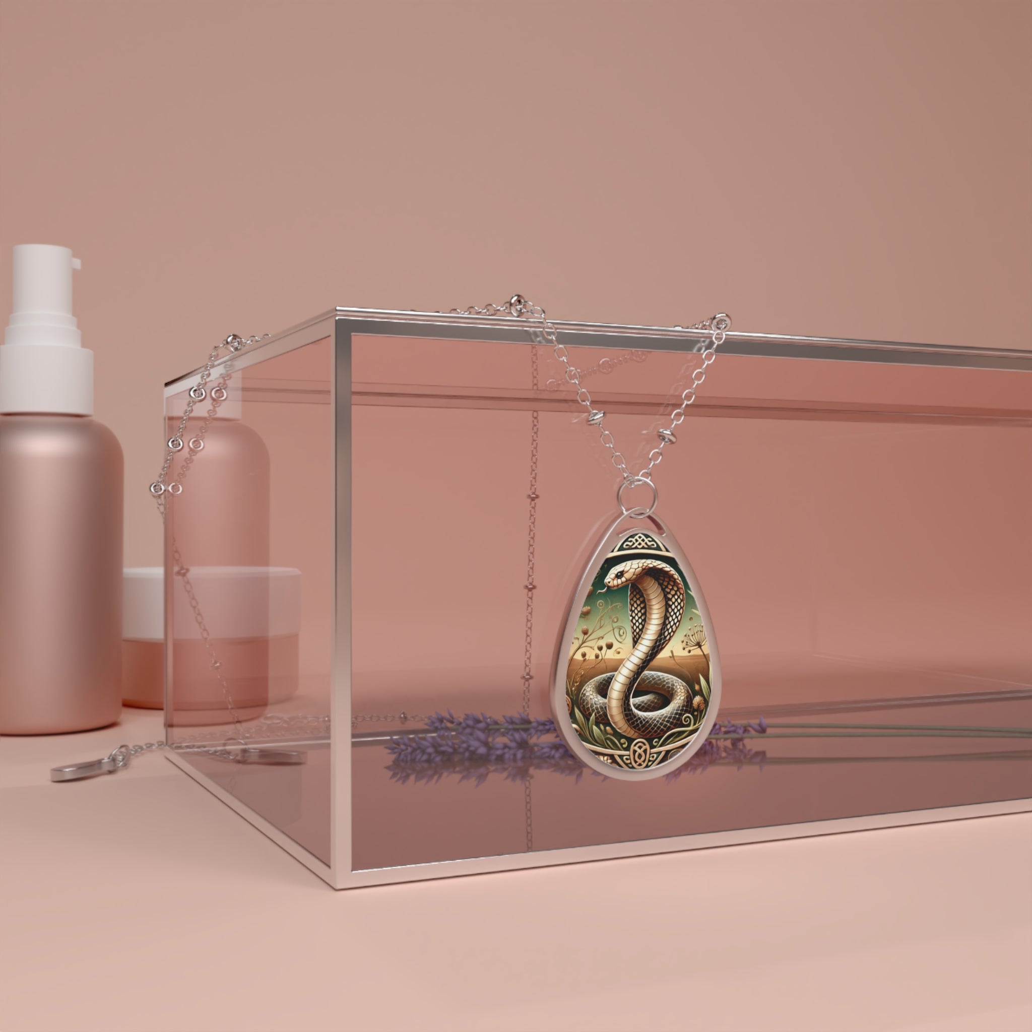 A silver necklace with a cobra pendant draped over a transparent box surrounded by lavender sprigs and cosmetic containers, set against a soft pink background. The pendant showcases a coiled cobra in intricate detail, surrounded by decorative patterns, symbolizing power and mystery.