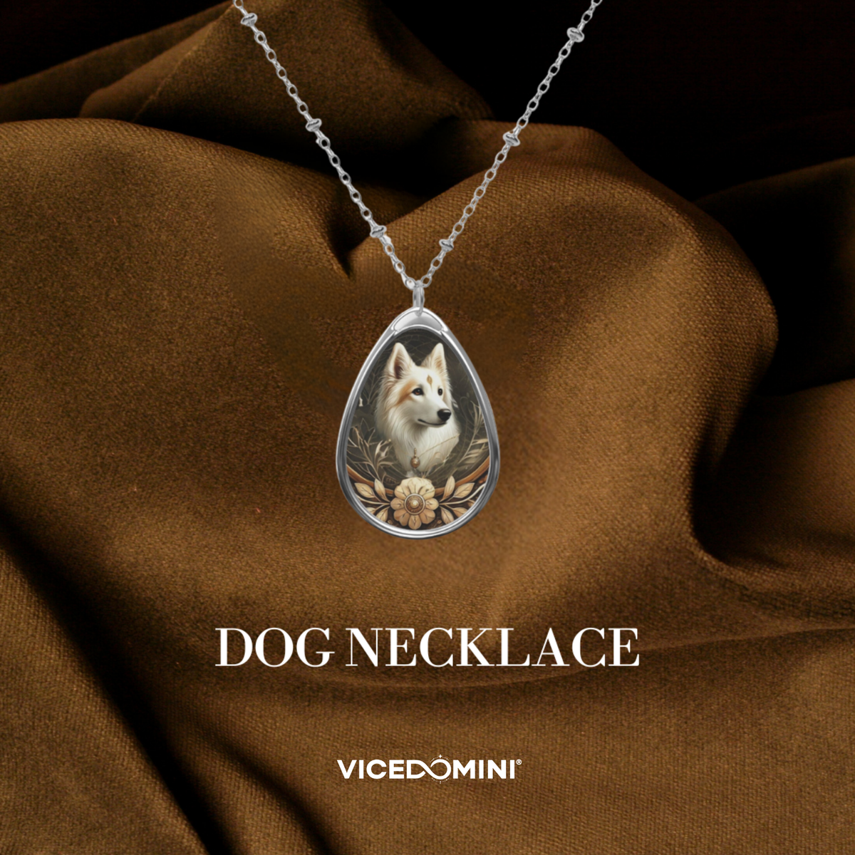 A silver teardrop pendant necklace featuring a custom pet portrait of a white dog with floral details, draped over a brown satin fabric background with the text 'DOG NECKLACE' and 'VICEDOMINI'.