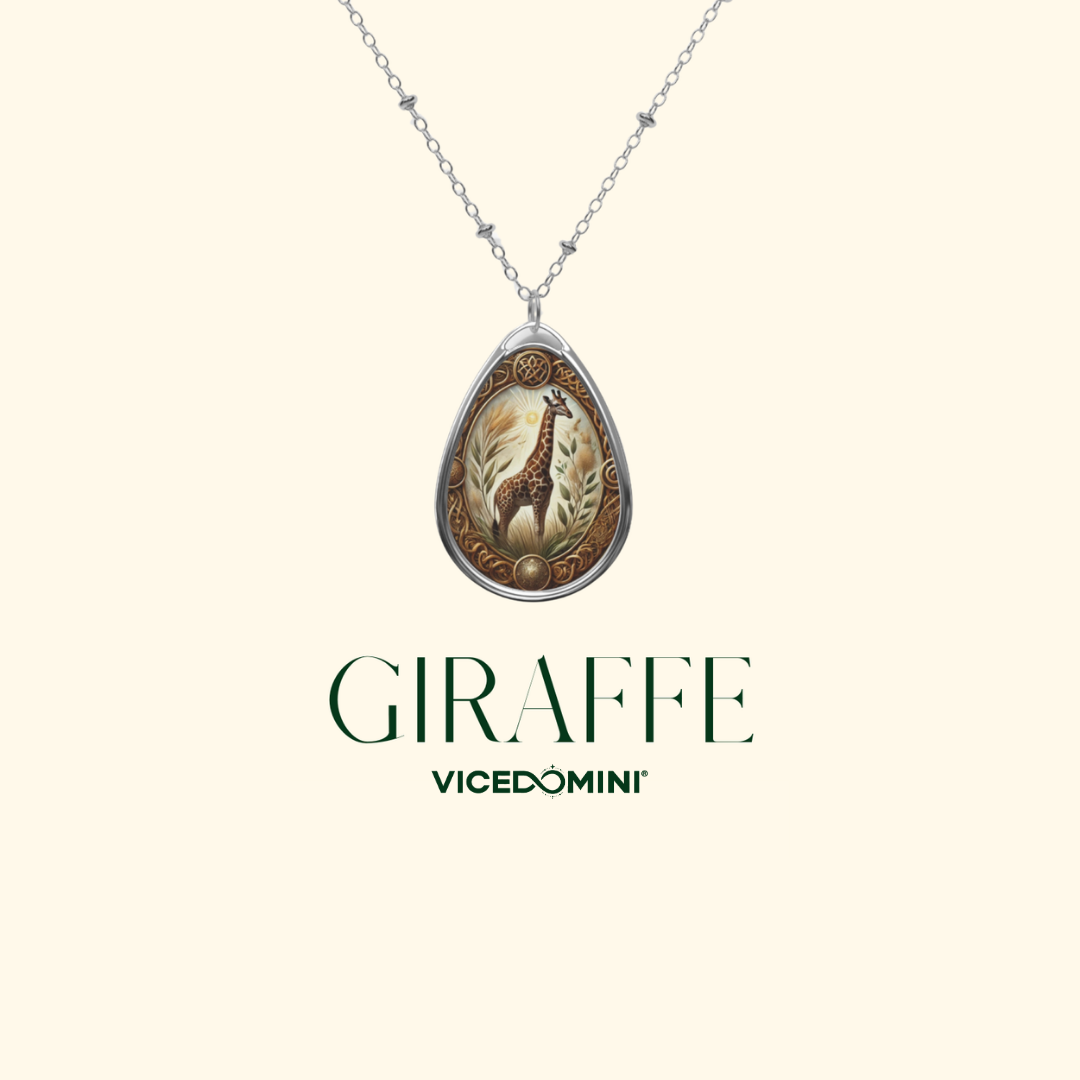A teardrop-shaped pendant necklace featuring an engraved giraffe design in brown, gold, and cream tones, suspended from a silver-toned chain. The brand name 'VICEDOMINI' and the word 'GIRAFFE' are printed below the pendant on a solid cream background.