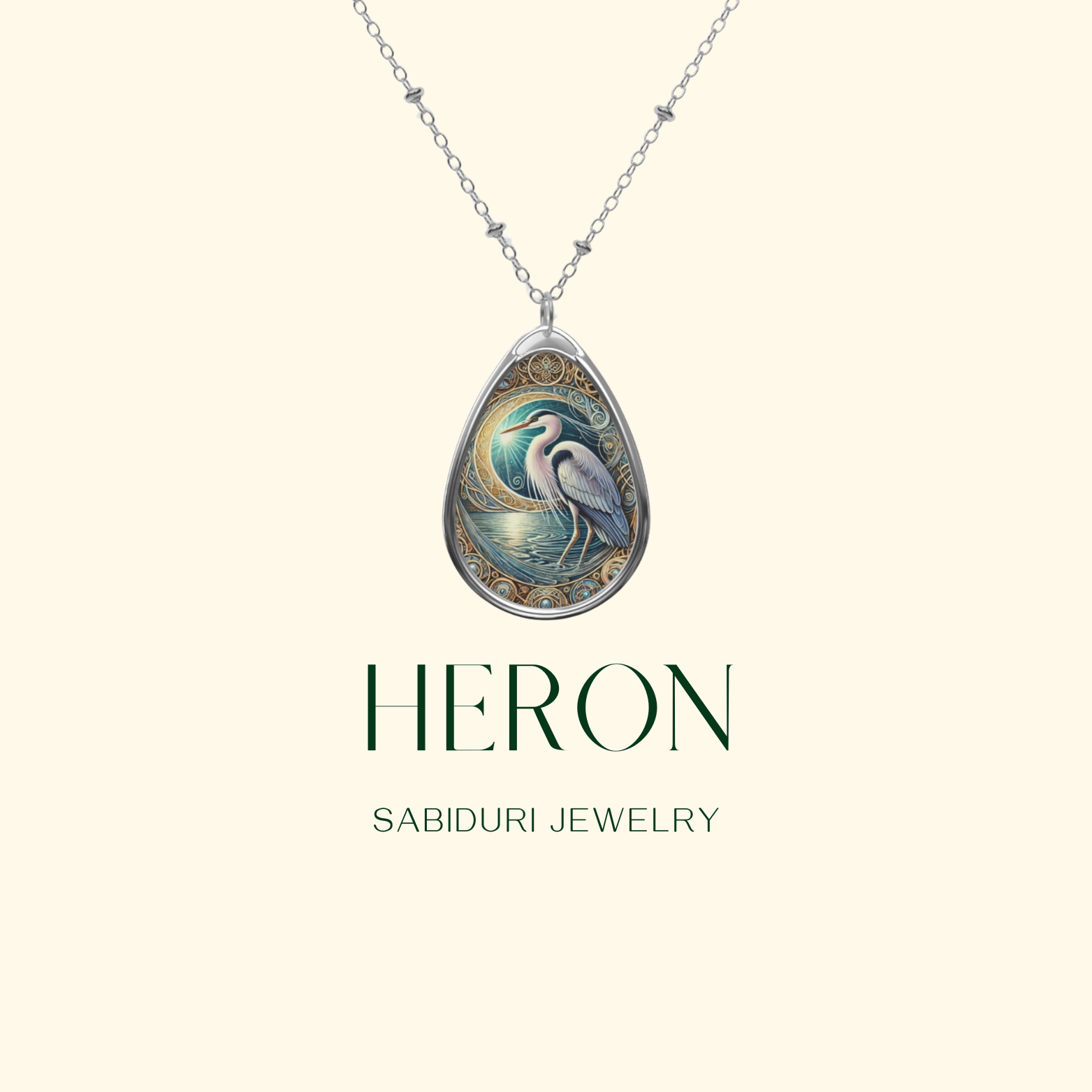 A silver teardrop-shaped pendant featuring an intricately detailed heron standing by a moonlit water scene, adorned with swirling gold embellishments. The necklace is displayed against a soft cream background with "HERON" and "SABIDURI JEWELRY" written below.