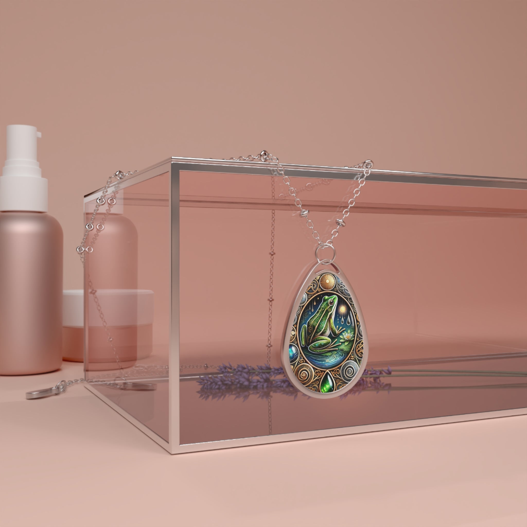 A lifestyle product shot featuring the frog necklace draped over a clear acrylic box, styled with lavender sprigs. The warm, neutral setting highlights the pendant’s intricate artistry and organic theme.