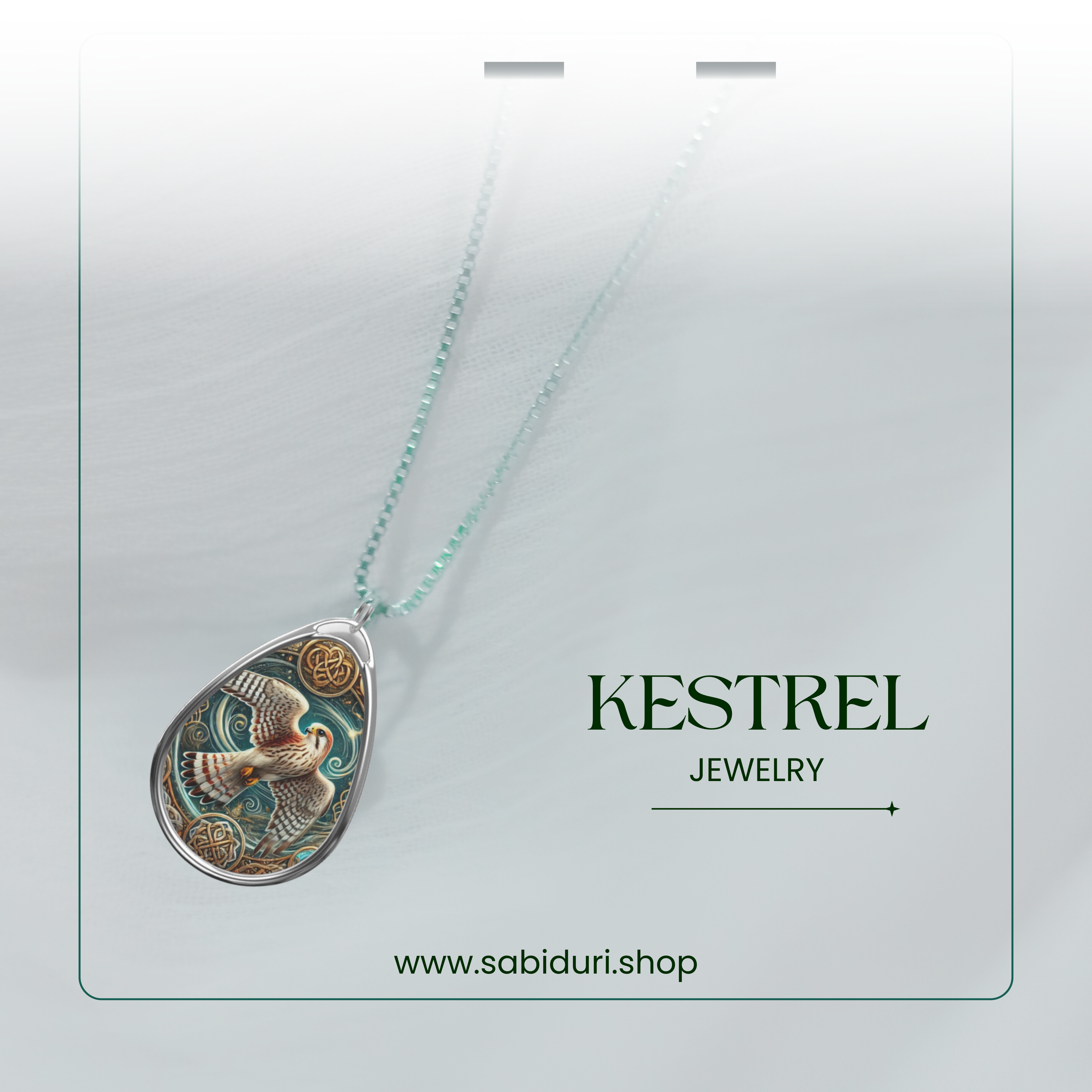 A sophisticated kestrel pendant with a silver frame, featuring a beautifully detailed bird in flight with ornate golden accents. The necklace is presented on a subtle white and green gradient background with "KESTREL JEWELRY" and "www.sabiduri.shop" in refined text.