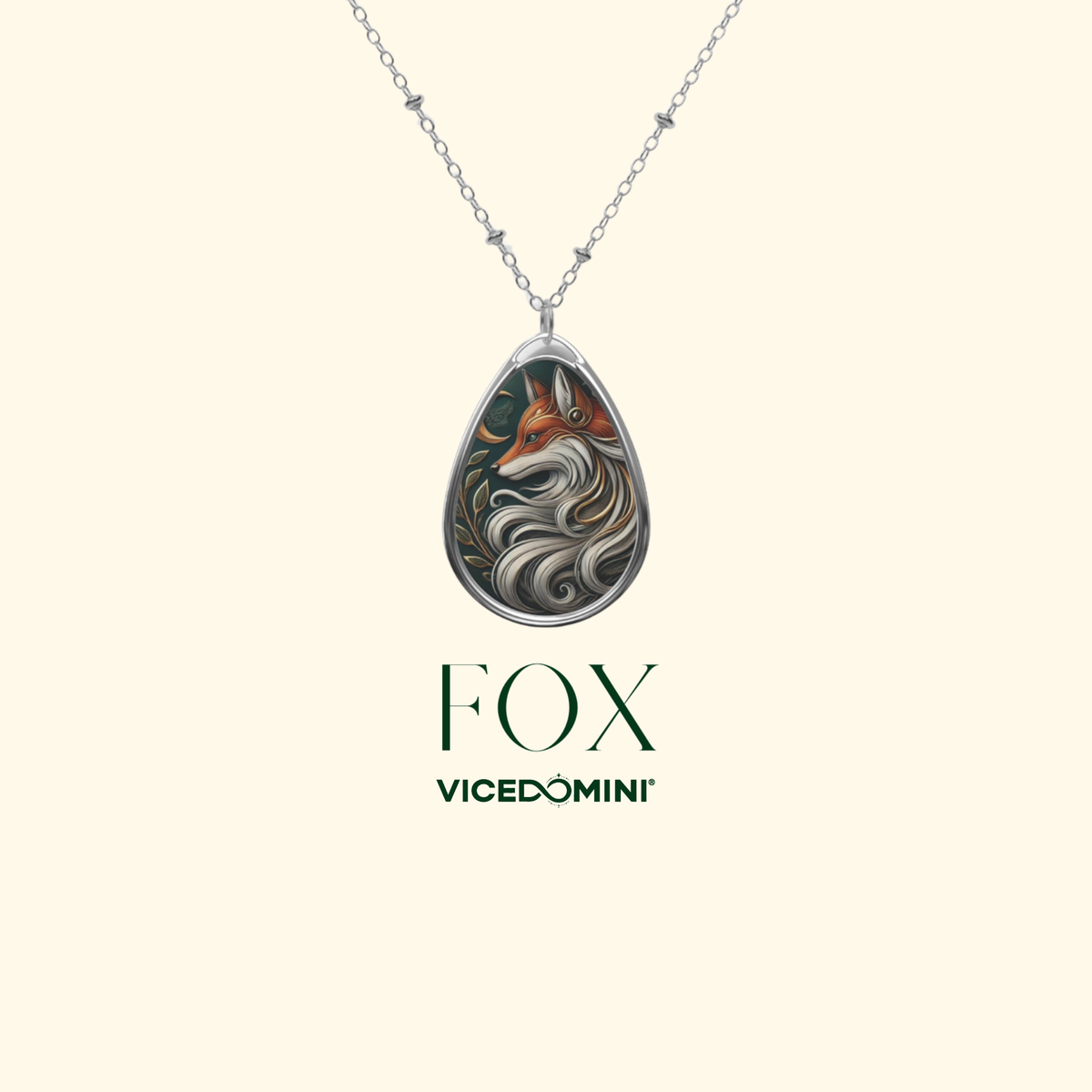 A silver teardrop pendant necklace featuring an intricate illustration of a fox with flowing white and gray fur details, shown on a light cream background with the brand name 'VICEDOMINI' and 'FOX' printed below.