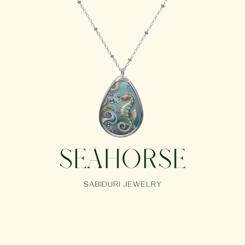 A close-up of a teardrop-shaped pendant featuring a detailed seahorse design with swirling ocean waves and bubble accents. The necklace is displayed against a soft, white textured background. The text "SEAHORSE JEWELRY" is written in green, with the URL "www.sabiduri.shop" at the bottom, all framed by a minimalistic green border.