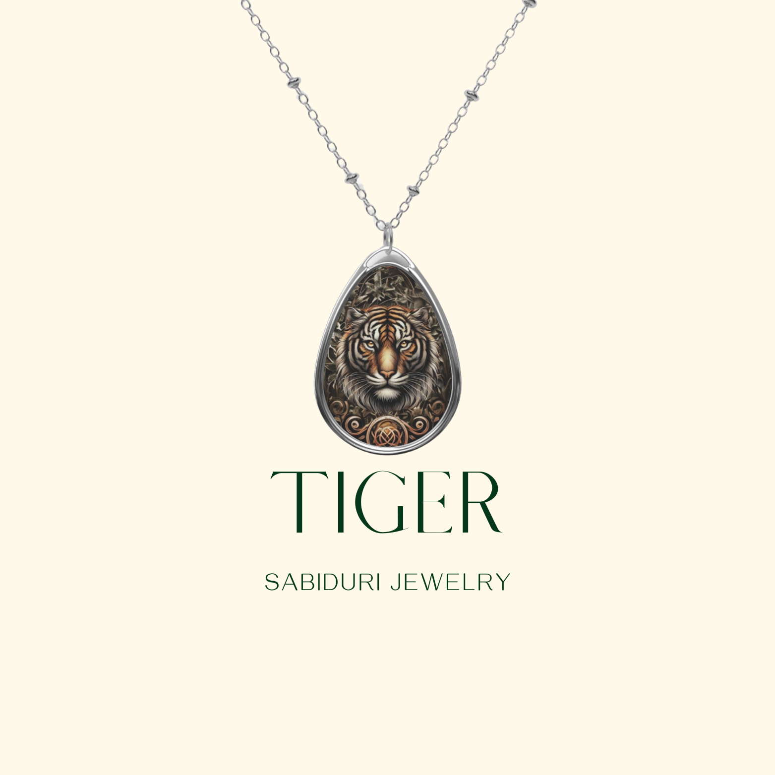 A silver necklace with a teardrop-shaped pendant featuring an intricate tiger design. The word "TIGER" is prominently displayed below the pendant, along with the brand name "SABIDURI JEWELRY" in a clean, serif font against a beige background.