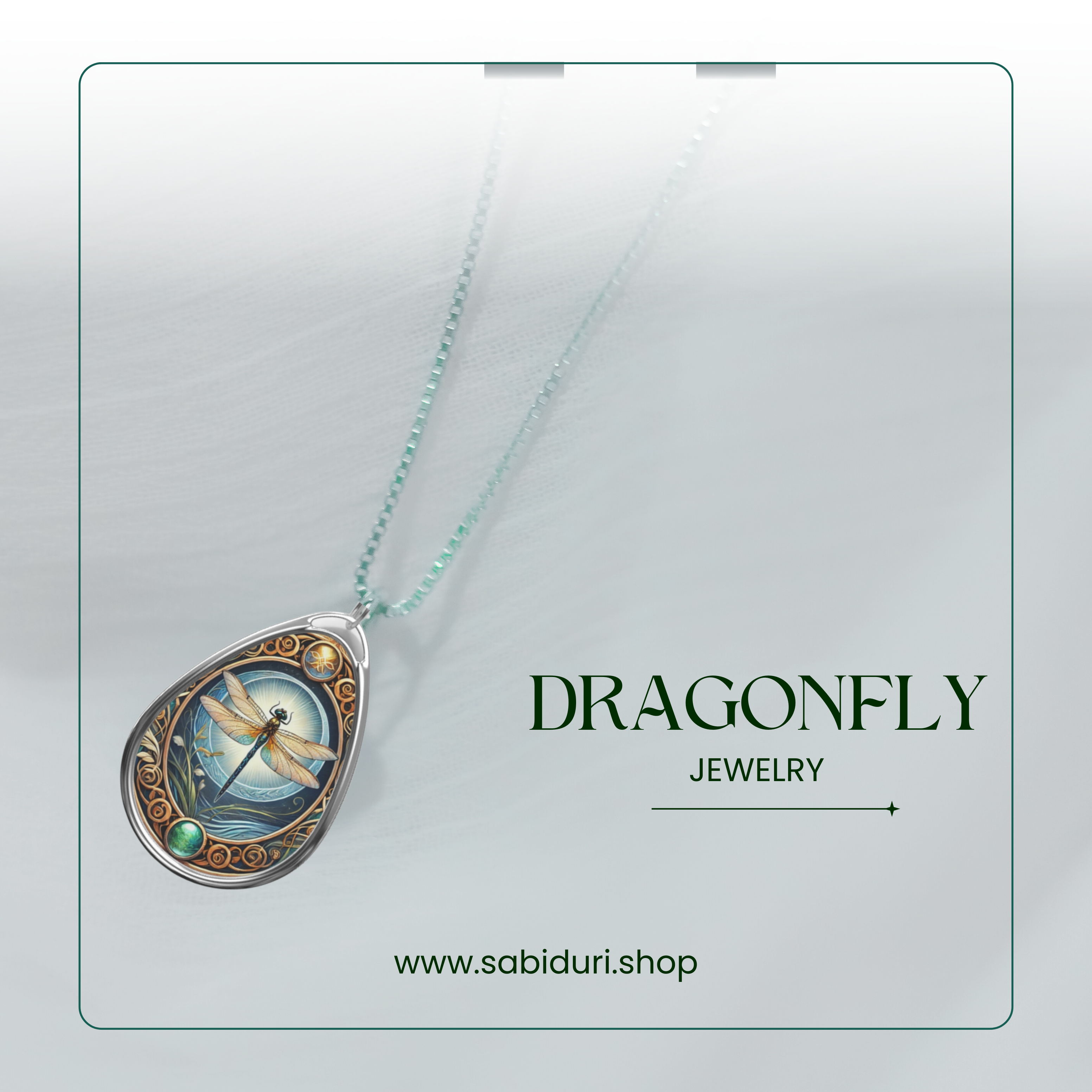 A silver dragonfly pendant necklace placed on a soft white textured background. The pendant shows a delicate dragonfly with a radiant background, surrounded by intricate golden designs and a green gemstone at the bottom. The text reads "DRAGONFLY Jewelry" with the website "www.sabiduri.shop" displayed at the bottom.