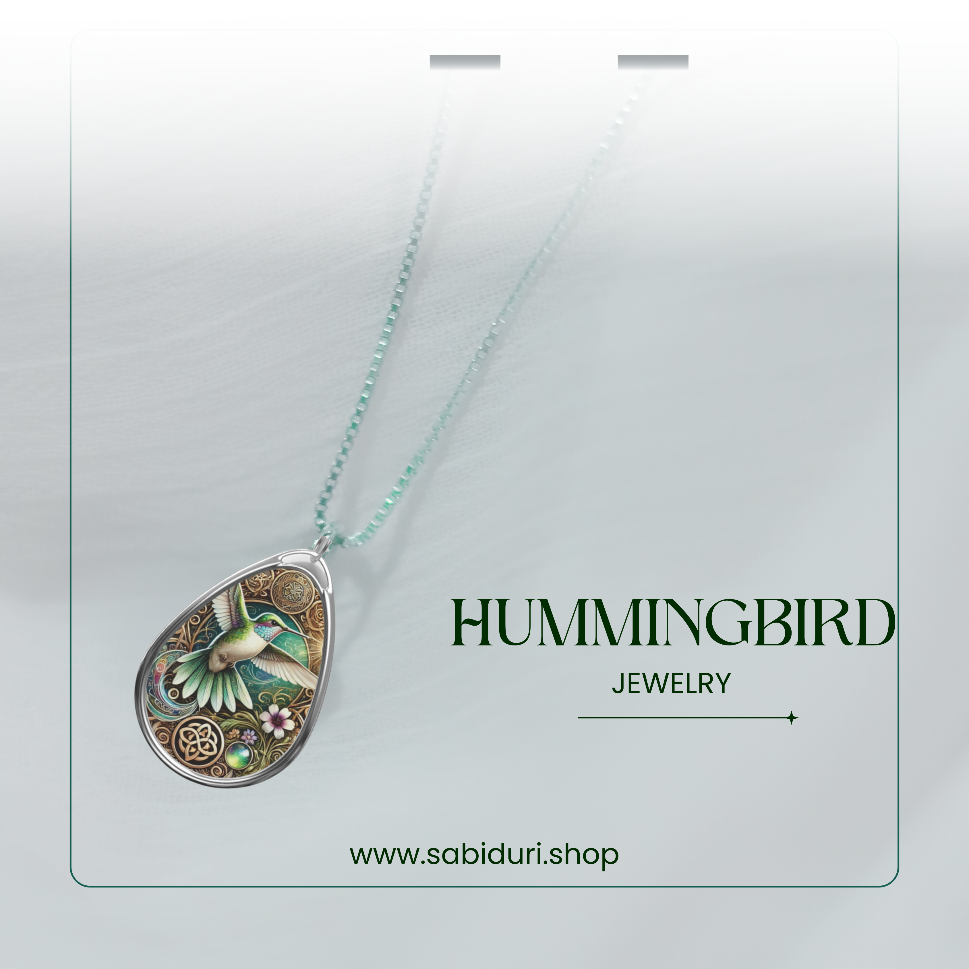 A softly lit close-up of the hummingbird necklace, hanging against a blurred white background. The elegant silver chain features subtle beaded details, and "HUMMINGBIRD JEWELRY" is displayed in a stylish font, enhancing the luxurious feel of the piece.