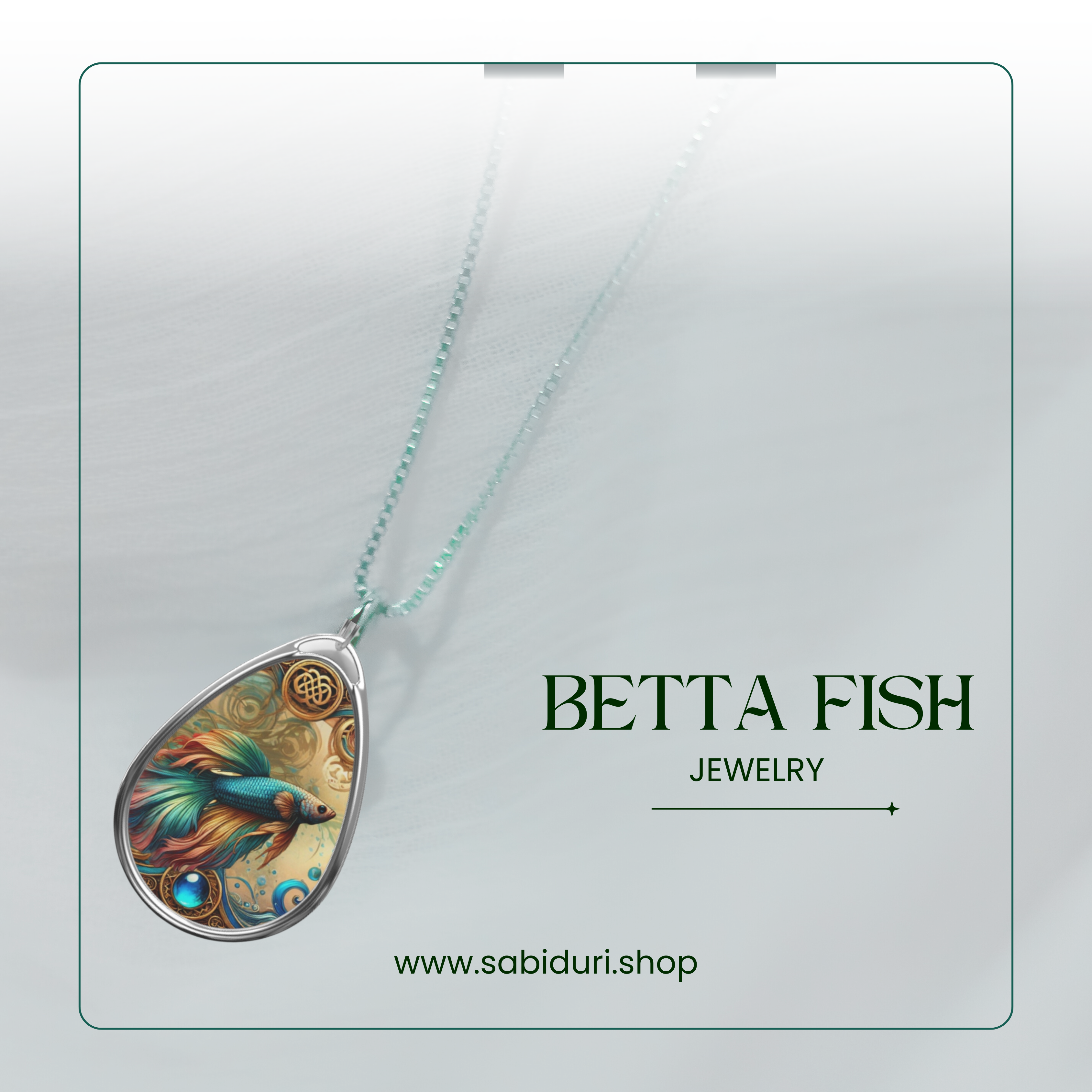 A Betta Fish necklace on a clean, white background with elegant branding. The teardrop pendant showcases a colorful Betta Fish design with swirling details and a gemstone accent. Text reads "Betta Fish Jewelry" and the website link "www.sabiduri.shop."