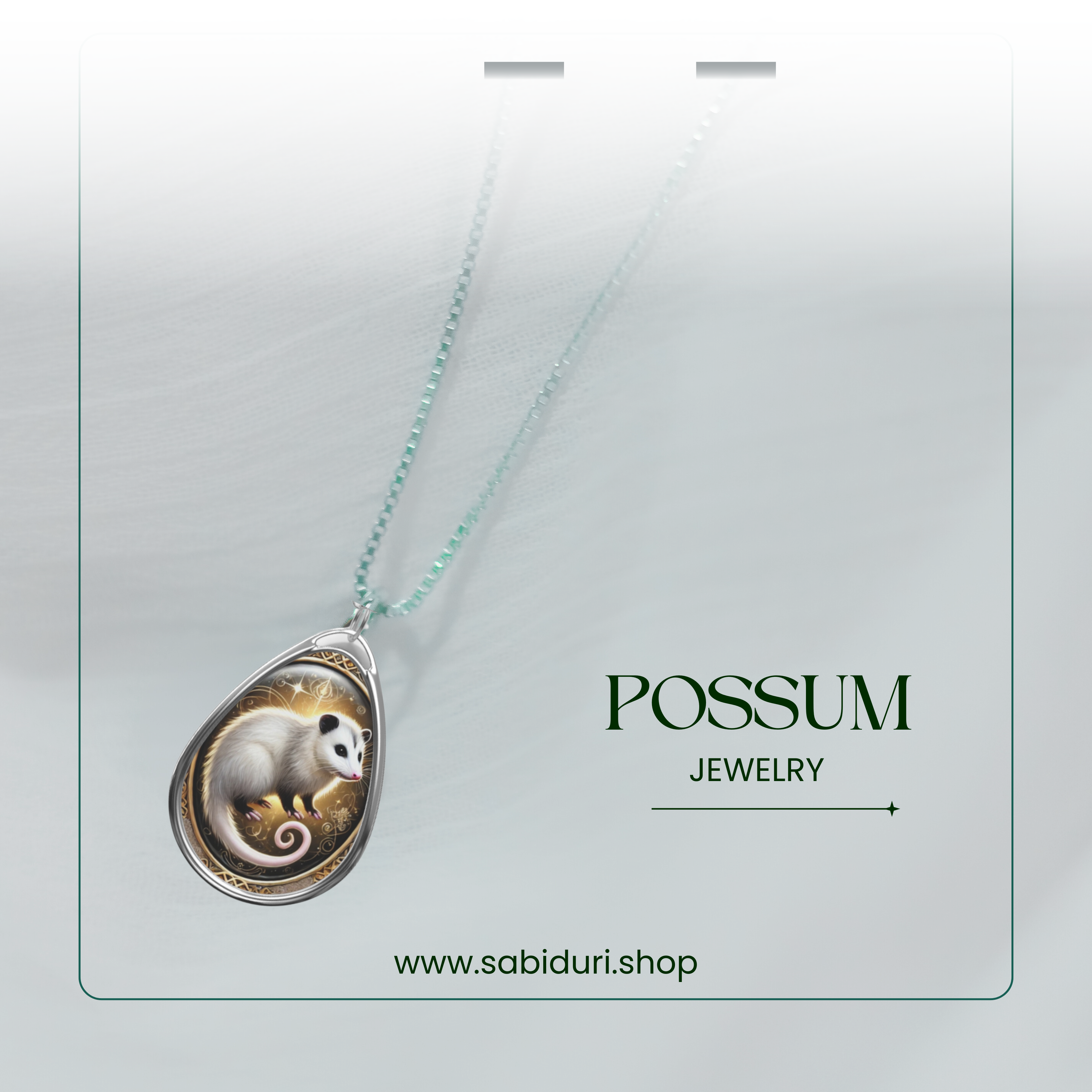 The possum pendant necklace is elegantly draped against a soft, white background. The silver chain connects to the intricately crafted pendant, which features a possum in a detailed golden and black backdrop. The text "POSSUM JEWELRY" appears with the website "www.sabiduri.shop."