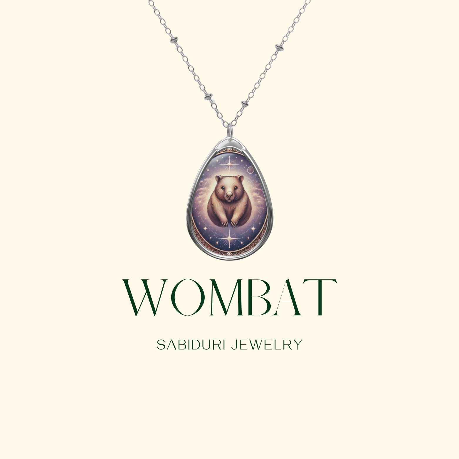 A close-up of a silver teardrop pendant with an intricately designed wombat against a mystical, starry backdrop. The pendant hangs from a delicate silver chain on a clean, light beige background with "Wombat" and "Sabiduri Jewelry" in refined typography.