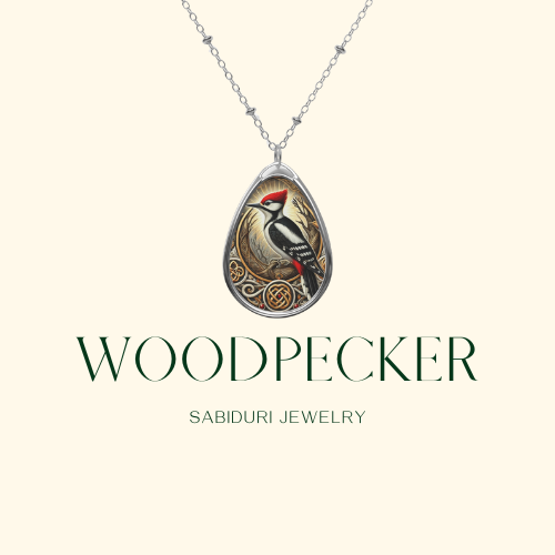 A silver necklace pendant featuring a woodpecker with bold red markings, set within a nature-inspired border, displayed on a minimalist cream background. The text reads "WOODPECKER Sabiduri Jewelry.