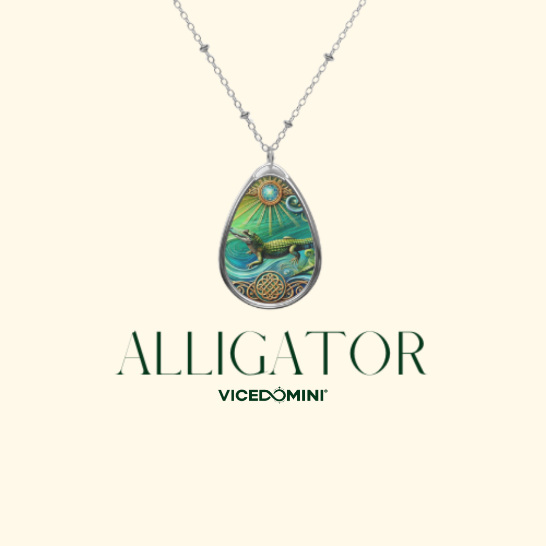 A silver teardrop pendant necklace featuring a colorful illustration of an alligator on a cream background, with the brand name 'ALLIGATOR' and sub-brand 'VICEDOMINI' printed below.