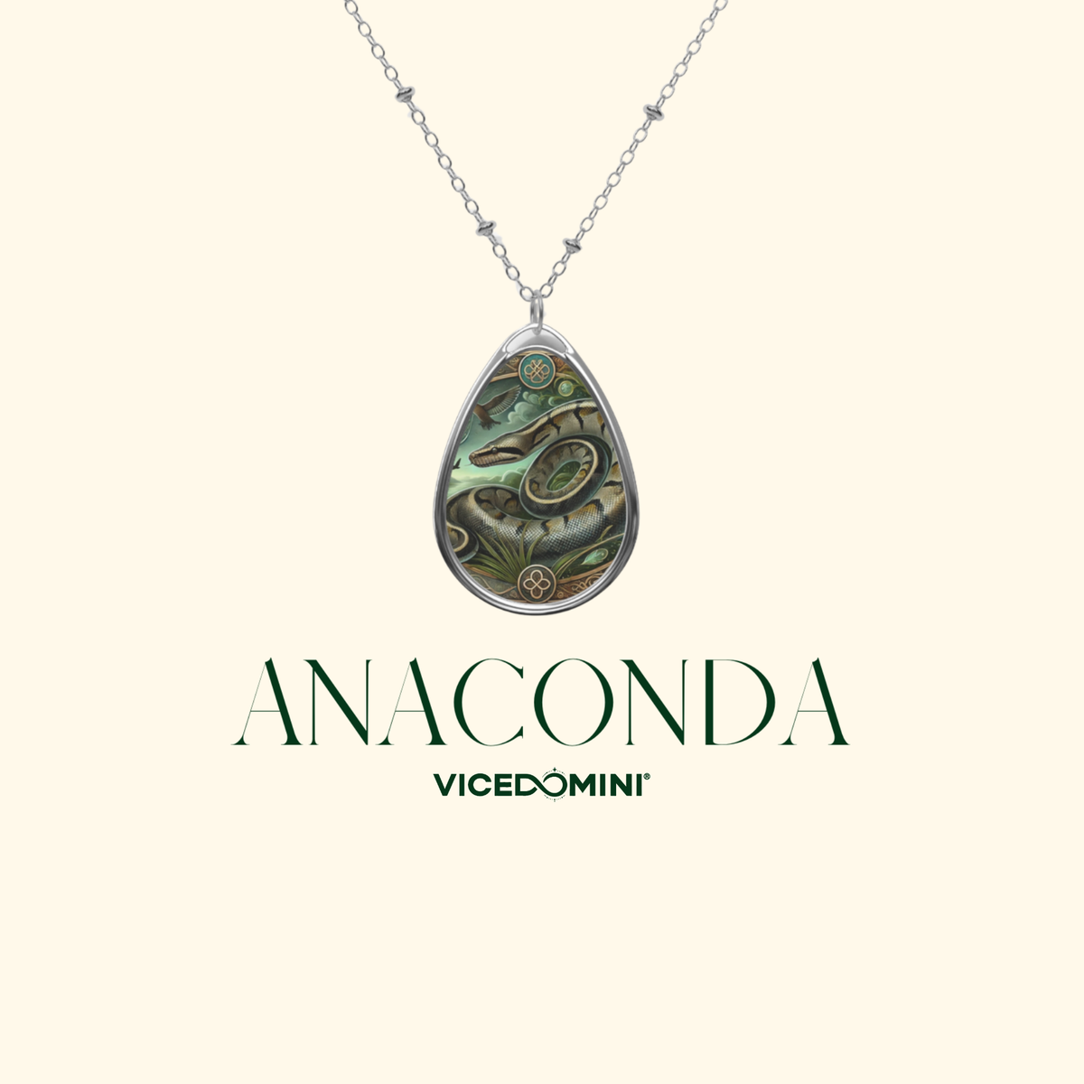 A teardrop-shaped pendant necklace featuring an abalone shell inlay with green, gold, and brown tones, suspended from a silver-toned chain. The brand name 'ANACONDA' is displayed below the pendant, with 'VICEDOMINI' underneath, all on a solid pale cream background.