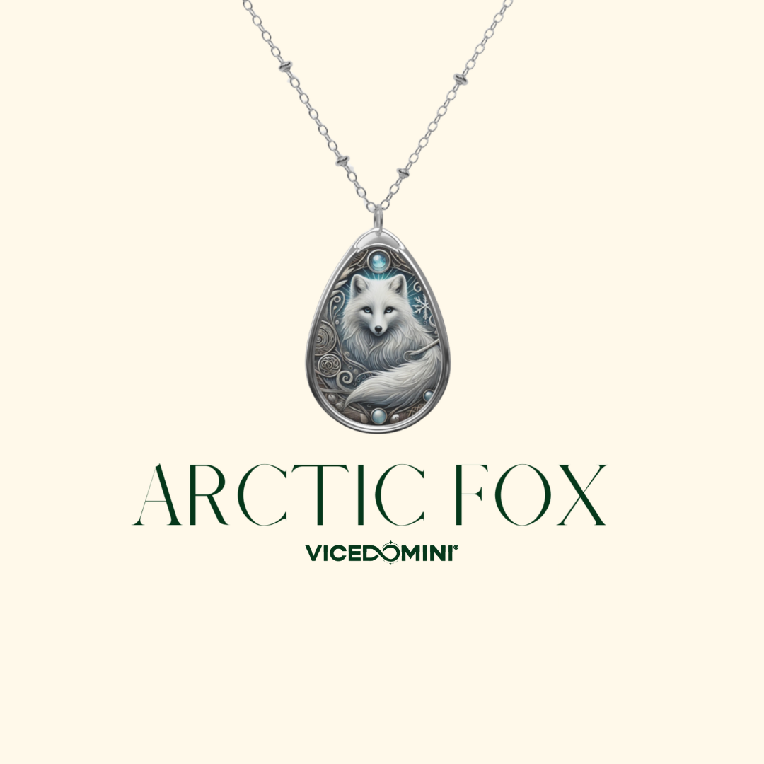 A silver teardrop pendant necklace featuring an engraved fox design with a small turquoise accent, shown against a cream background with the text 'ARCTIC FOX' and 'VICEDOMINI' below.