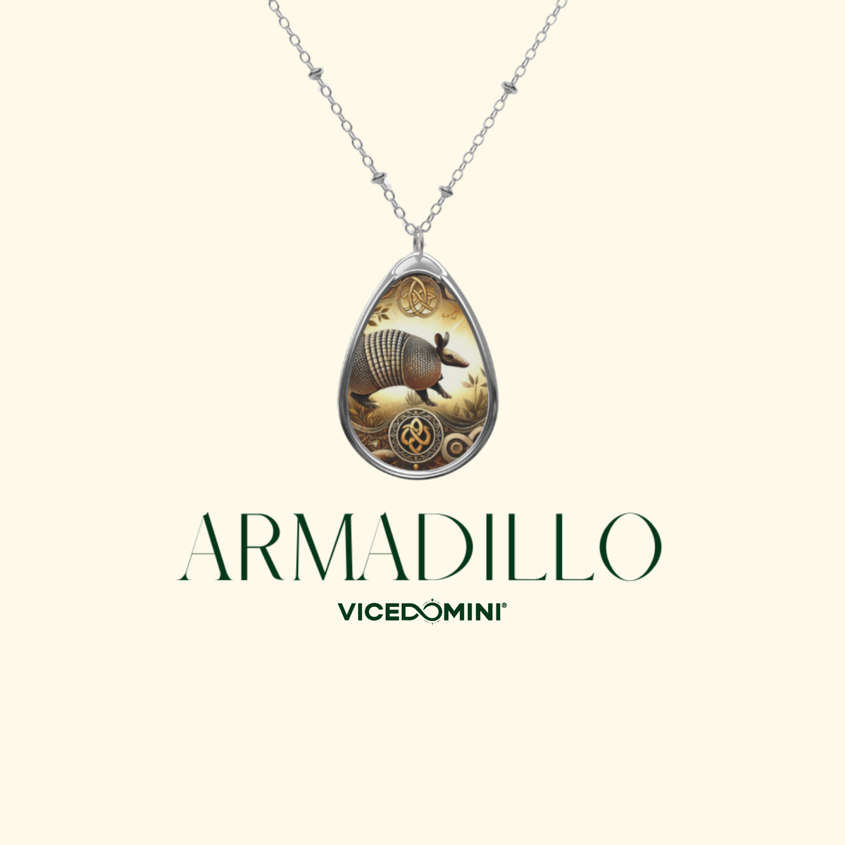 Silver-tone necklace with a teardrop pendant featuring an armadillo illustration and ornate gold detailing, shown on a cream background with the text 'ARMADILLO' and 'VICEDOMINI' below.