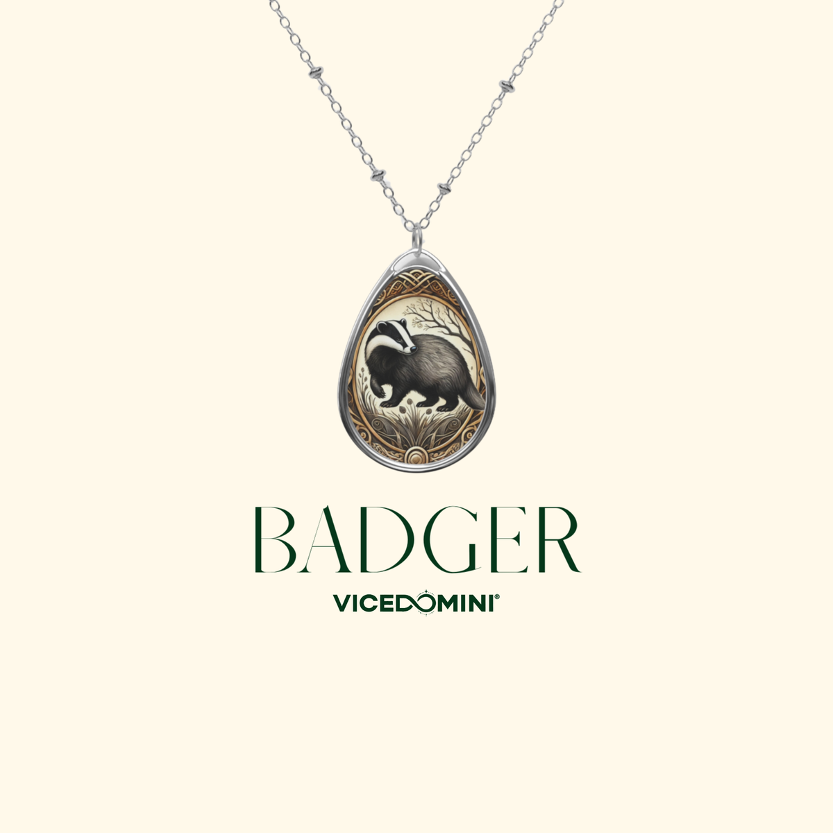 A teardrop pendant necklace featuring an engraved badger design with a silver-toned chain, centered on a light cream background with the text 'BADGER' and 'VICEDOMINI' below.