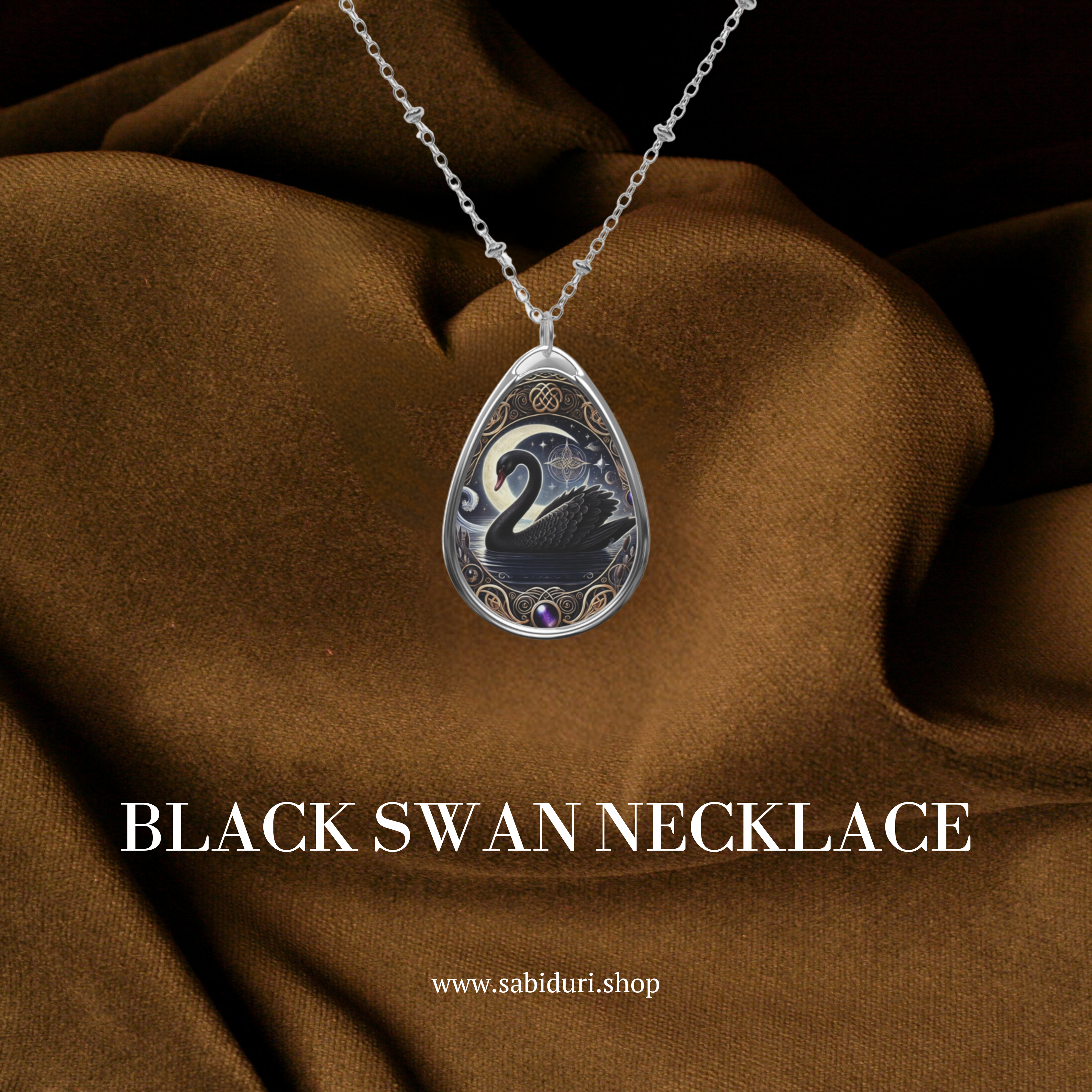 The Black Swan necklace displayed against a rich brown fabric background, emphasizing its intricate details. The pendant features a black swan swimming under a starry night sky, encased in an ornate gold frame with Celtic motifs. Below the necklace, the text "BLACK SWAN NECKLACE" and "www.sabiduri.shop" are visible.