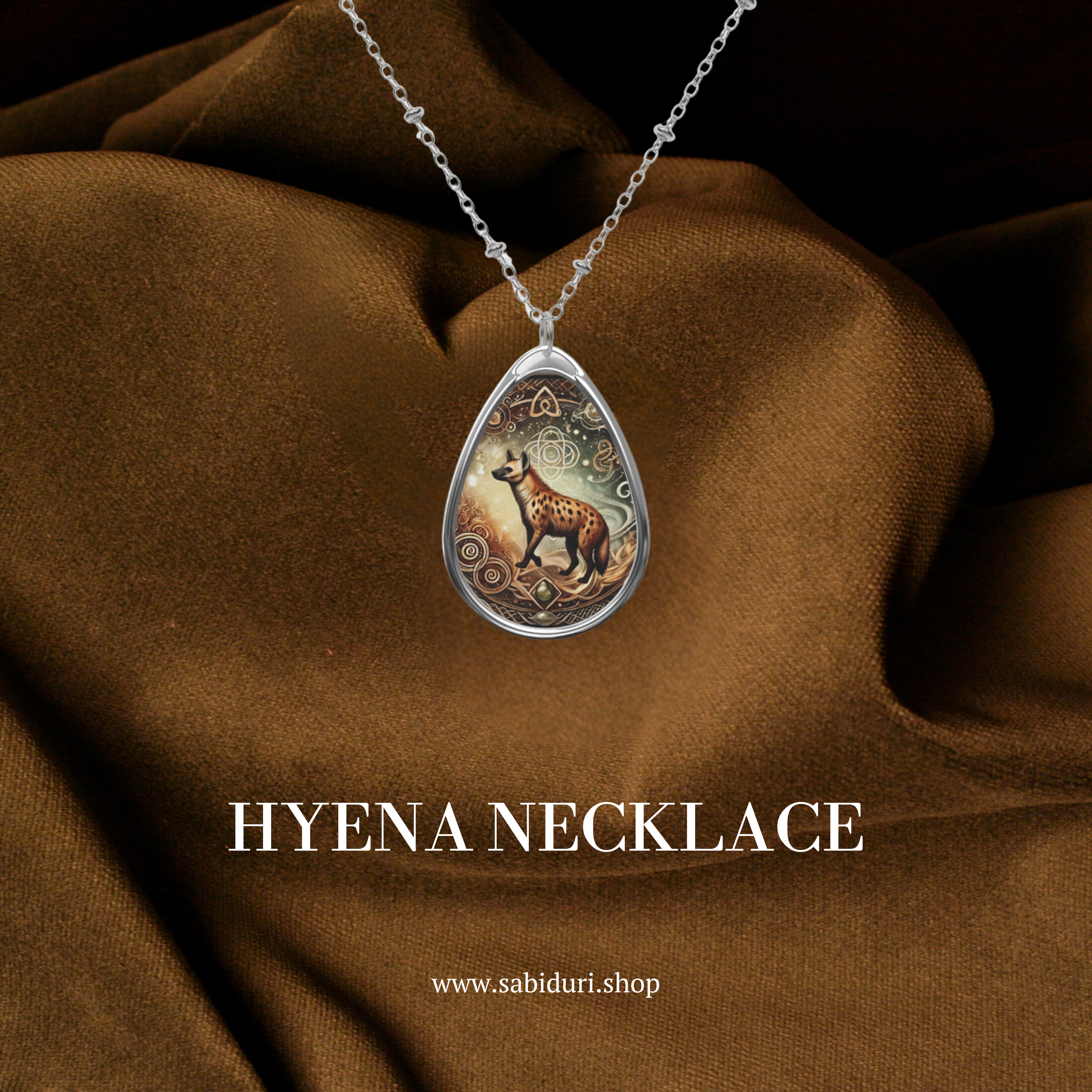 The Hyena Spirit Animal necklace draped over rich brown fabric, highlighting its intricate artwork. The text "HYENA NECKLACE" and "www.sabiduri.shop" appear below, emphasizing the jewelry’s elegance and brand identity.