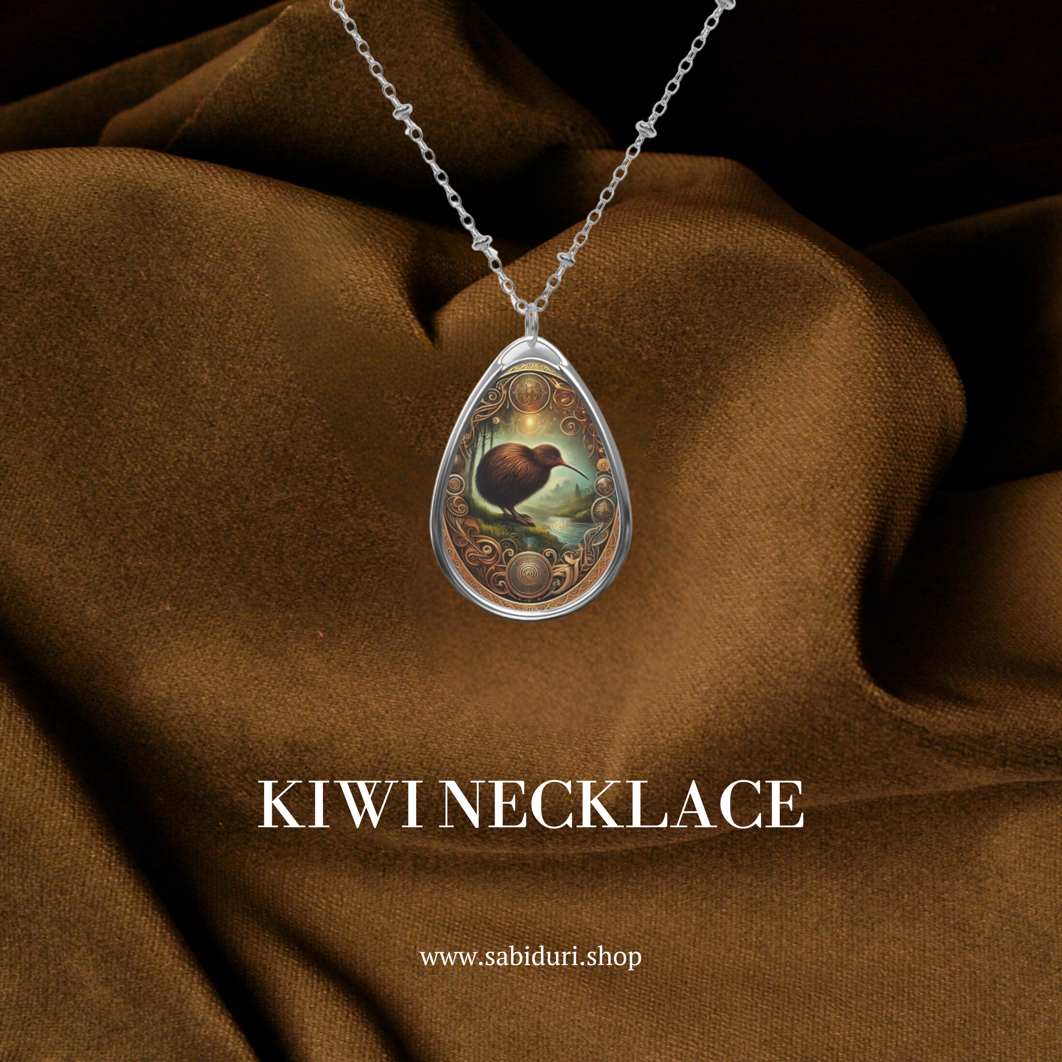 A beautifully crafted Kiwi spirit animal necklace with a teardrop pendant, featuring an intricate illustration of a kiwi bird in a mystical setting. The pendant is encased in silver with ornate golden details, hanging against a rich brown fabric backdrop. Text reads 'KIWI NECKLACE' and 'www.sabiduri.shop.'