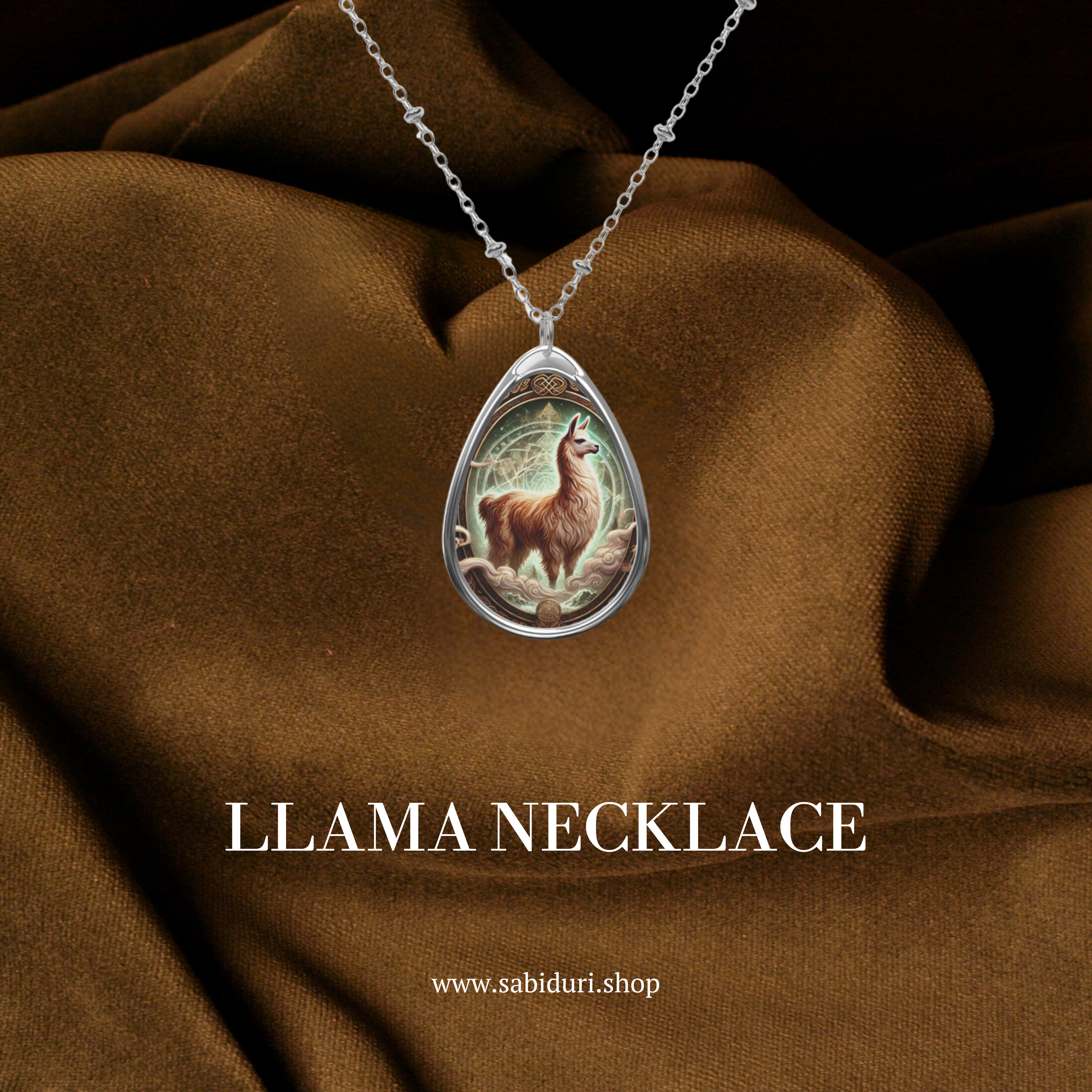 A silver teardrop pendant necklace featuring an intricate illustration of a majestic llama standing on rocky terrain, with glowing mystical energy swirling around it. The pendant is set against a rich brown fabric backdrop, emphasizing its earthy and spiritual essence. The text below reads: "LLAMA NECKLACE" with the website "www.sabiduri.shop."