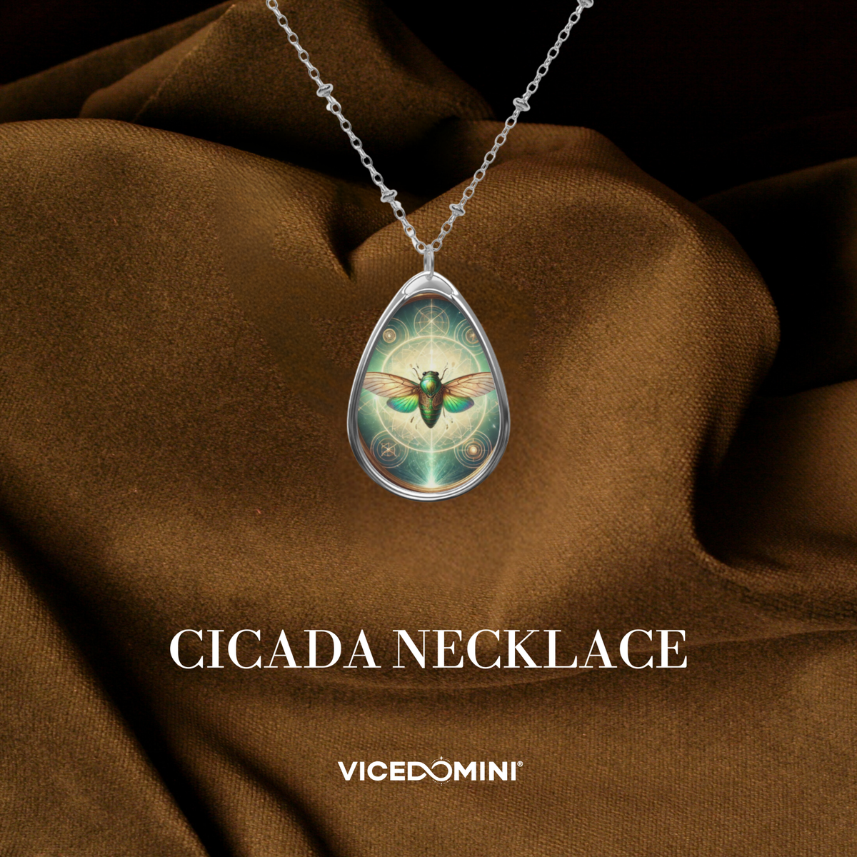 A cicada spirit animal necklace placed on luxurious brown fabric, with fine details of wings, green gemstone accents, and text "Cicada Necklace" and logo "VICEDOMINI".