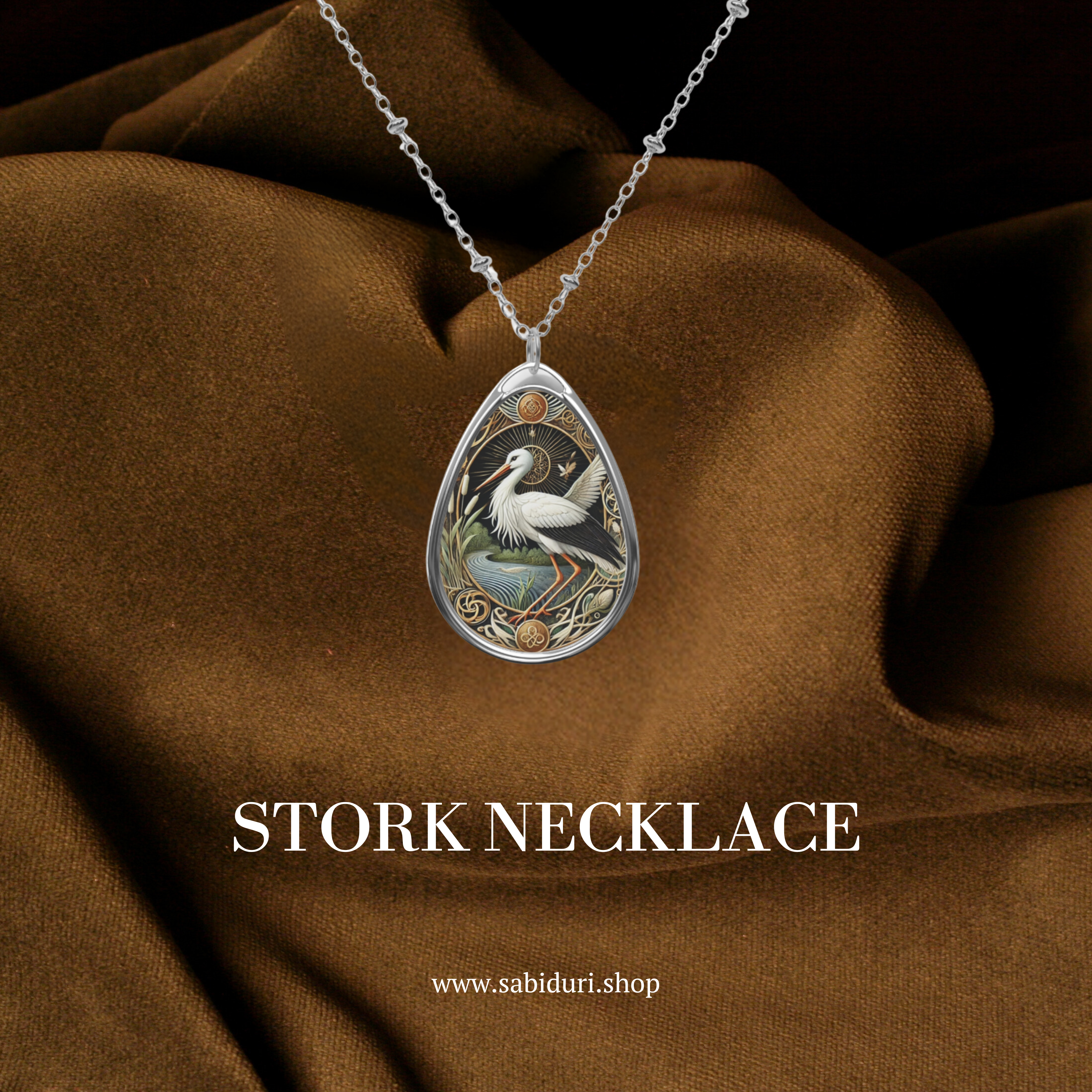 The stork spirit animal necklace presented on a luxurious brown fabric background, showcasing intricate details of the stork design with the text "Stork Necklace" and the website link (www.sabiduri.shop)