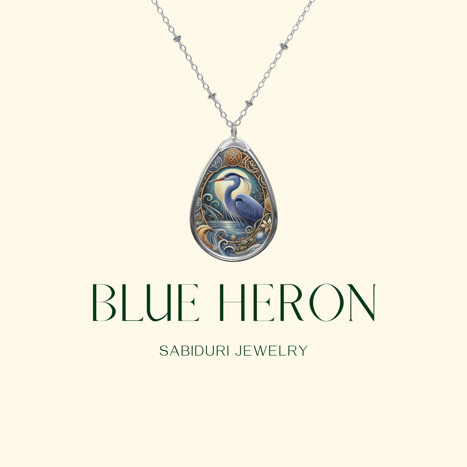 A silver necklace pendant featuring a blue heron with surrounding water and foliage details, set against a minimalist cream background. The text reads "BLUE HERON Sabiduri Jewelry," accentuating the pendant's serene design.