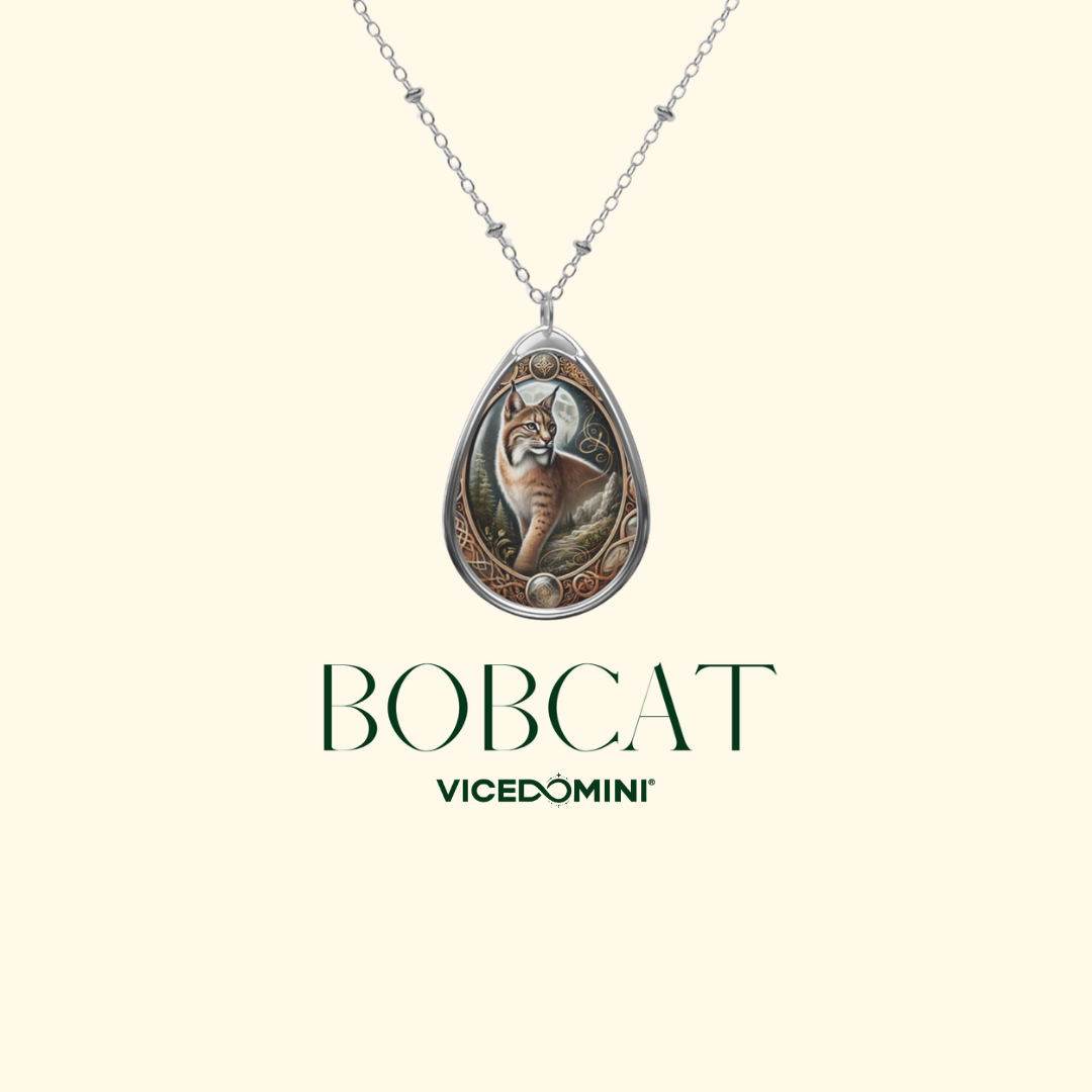 A silver teardrop pendant necklace featuring an illustrated bobcat in the center, shown on a light cream background with the text 'BOBCAT' and 'VICEDOMINI' below.