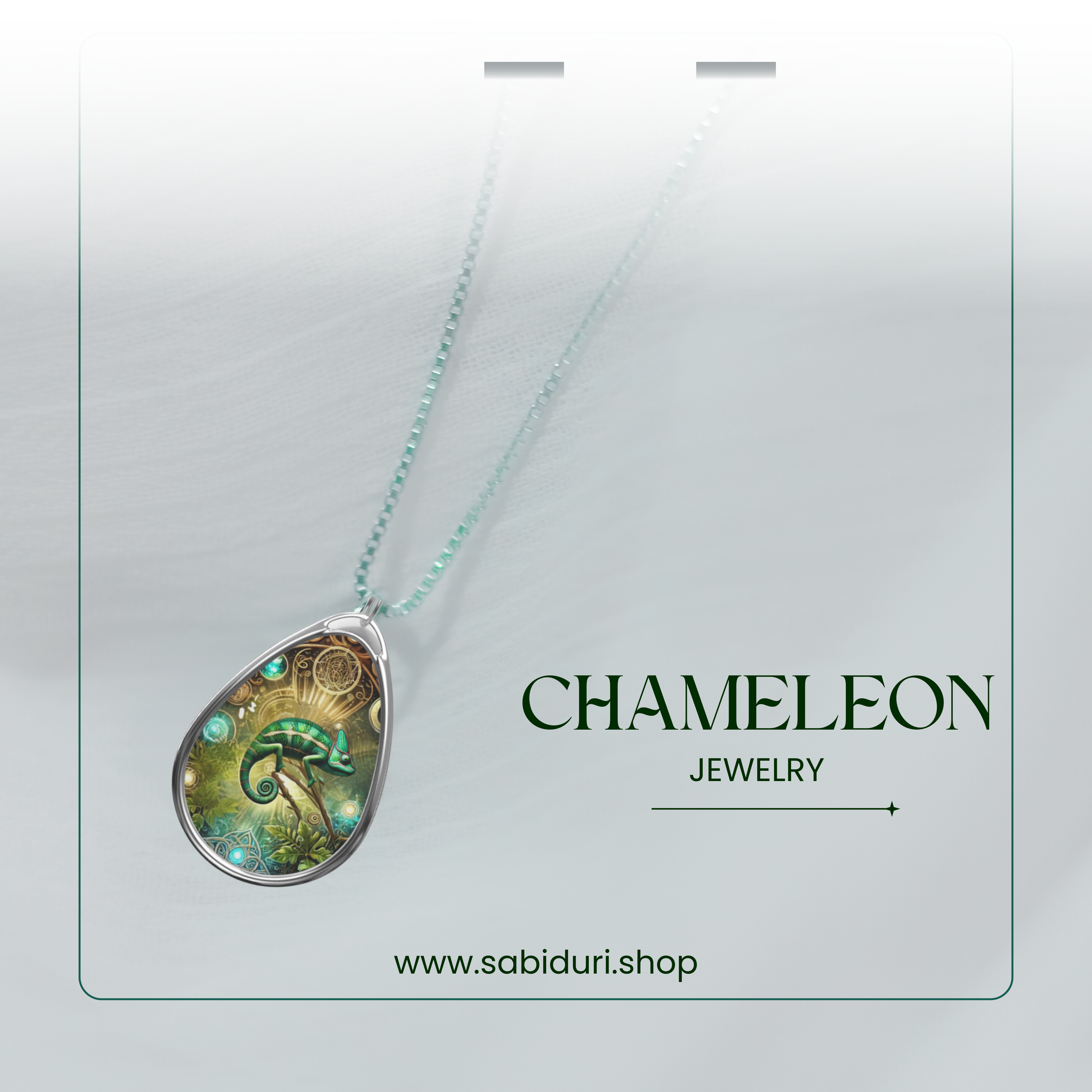 A delicate chameleon pendant necklace presented on an elegant jewelry packaging design with soft, blurred fabric texture in the background. The vibrant green chameleon and gold-accented design pop against the sophisticated frame, with the words "Chameleon Jewelry" and "www.sabiduri.shop" adding a polished branding touch.