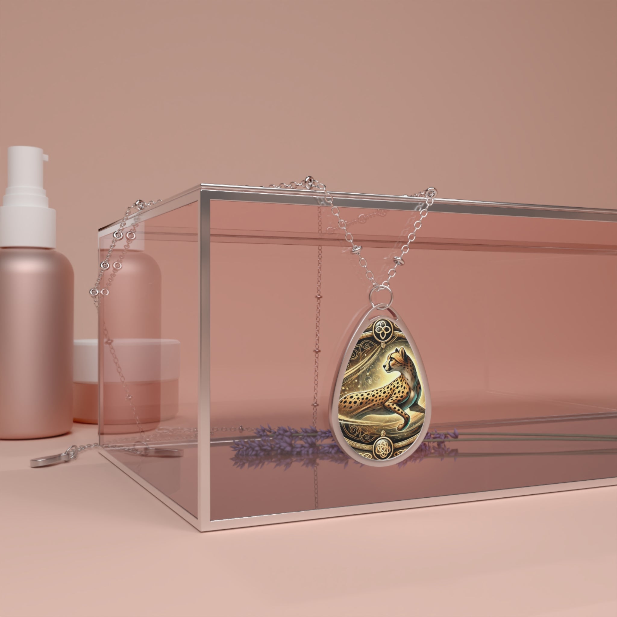 A beautifully crafted teardrop-shaped pendant featuring a cheetah in motion, set against intricate golden filigree. The necklace drapes over a glass box with soft, neutral tones in the background, creating a luxurious and elegant display. A sprig of lavender adds a natural touch to the composition.