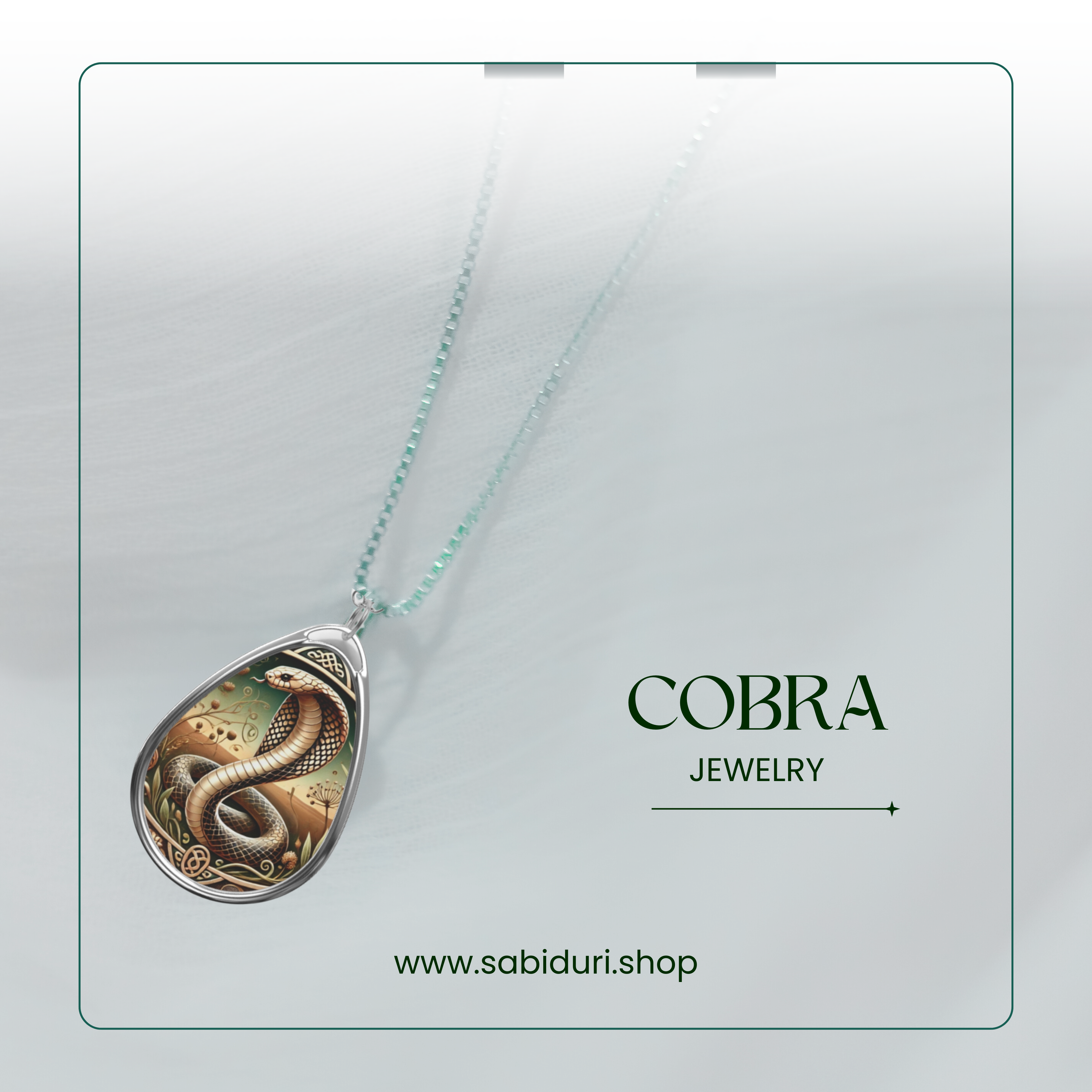 A cobra pendant necklace displayed on a textured white background. The pendant features a finely detailed cobra with its hood flared, set against a background of desert and foliage motifs, framed by ornate borders. The text reads "COBRA Jewelry" and includes the website "www.sabiduri.shop.
