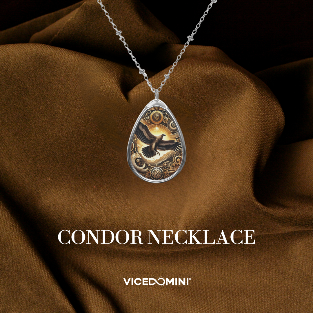 A teardrop-shaped silver pendant necklace featuring a detailed condor illustration with gold and black tones, displayed on draped brown fabric with the text 'CONDOR NECKLACE' and 'VICEDOMINI' below.