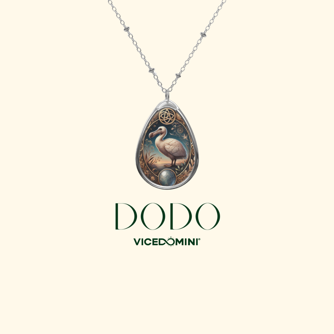 A teardrop-shaped pendant necklace with a silver-toned chain, featuring an illustrated bird and ornate decorative details, shown on a light cream background with the brand name DODO and Vicedomini below.
