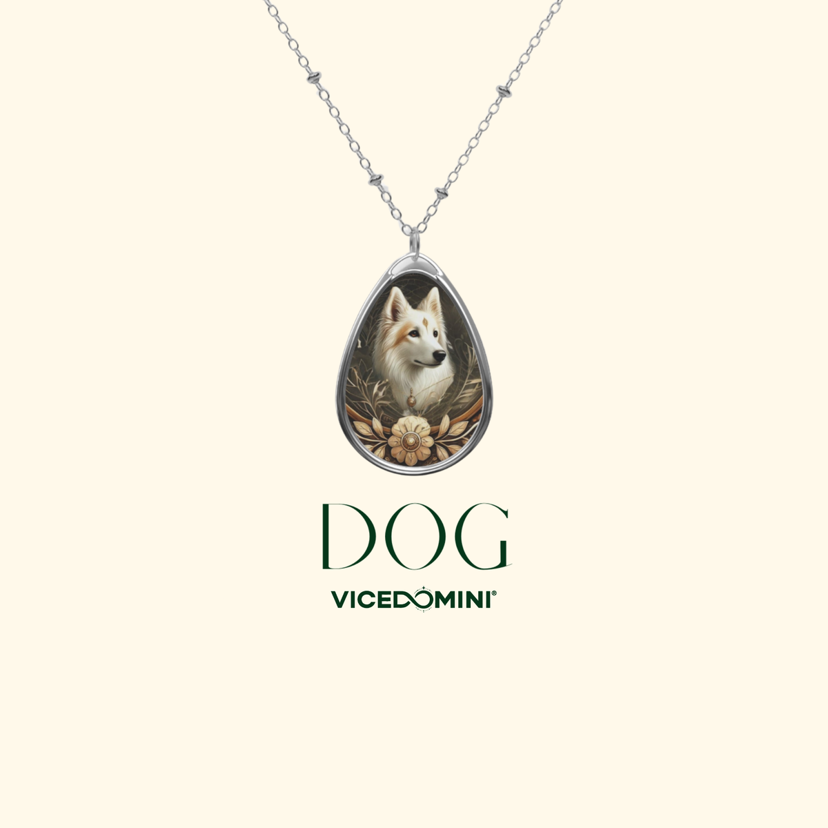 A silver teardrop pendant necklace featuring an illustration of a white dog surrounded by gold-toned leaves and a flower, shown on a cream background with the text 'DOG VICEDOMINI' below.