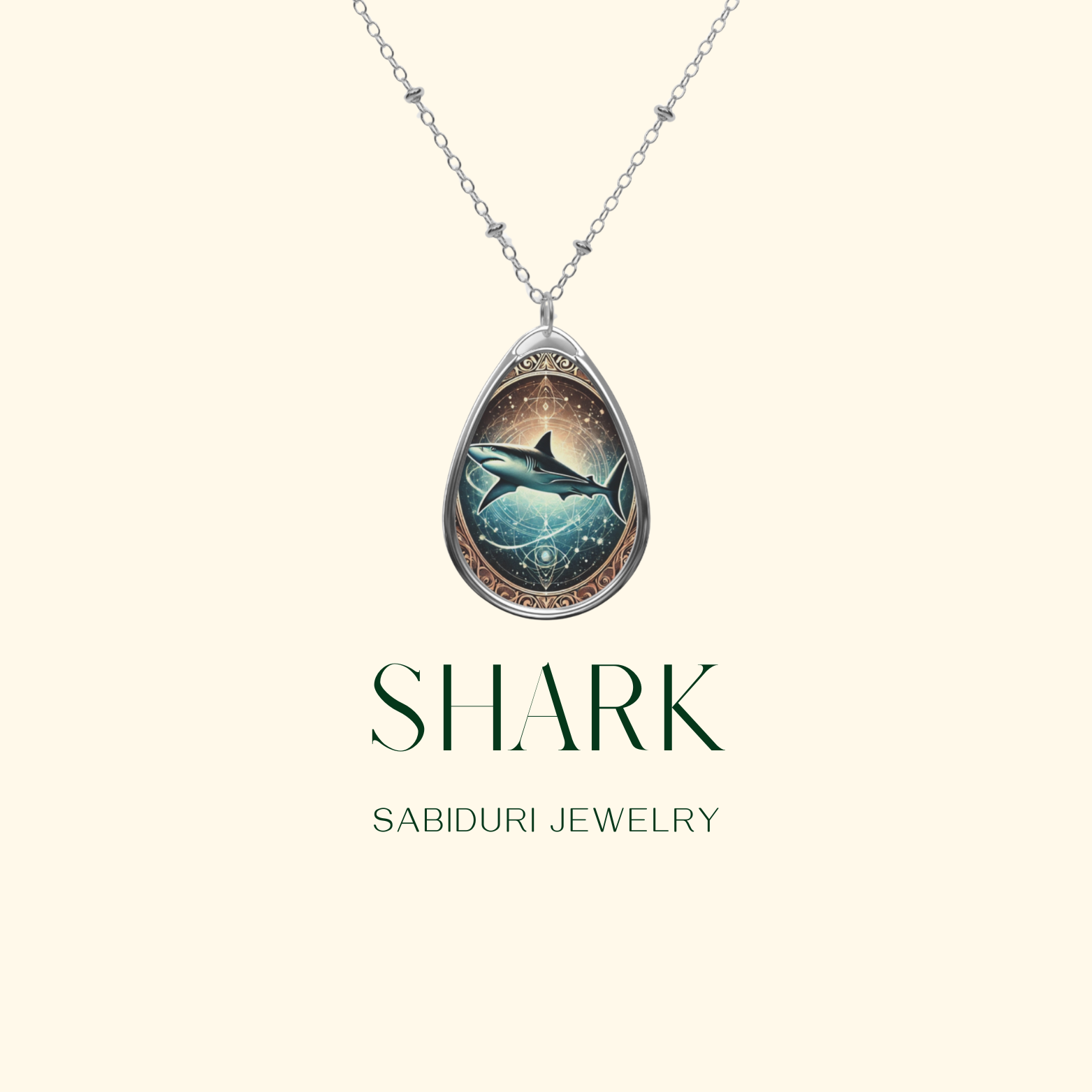 A minimalist product display featuring a silver shark pendant necklace against a light cream background. The pendant showcases a celestial-style shark surrounded by geometric patterns, with "SHARK" and "SABIDURI JEWELRY" text in elegant green typography.