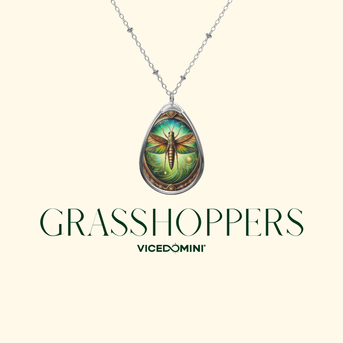 A teardrop-shaped pendant necklace featuring a detailed dragonfly illustration in green, blue, and gold tones, suspended from a silver chain. The brand name 'GRASSHOPPERS' and sub-brand 'VICEDOMINI' are printed below on a light cream background.
