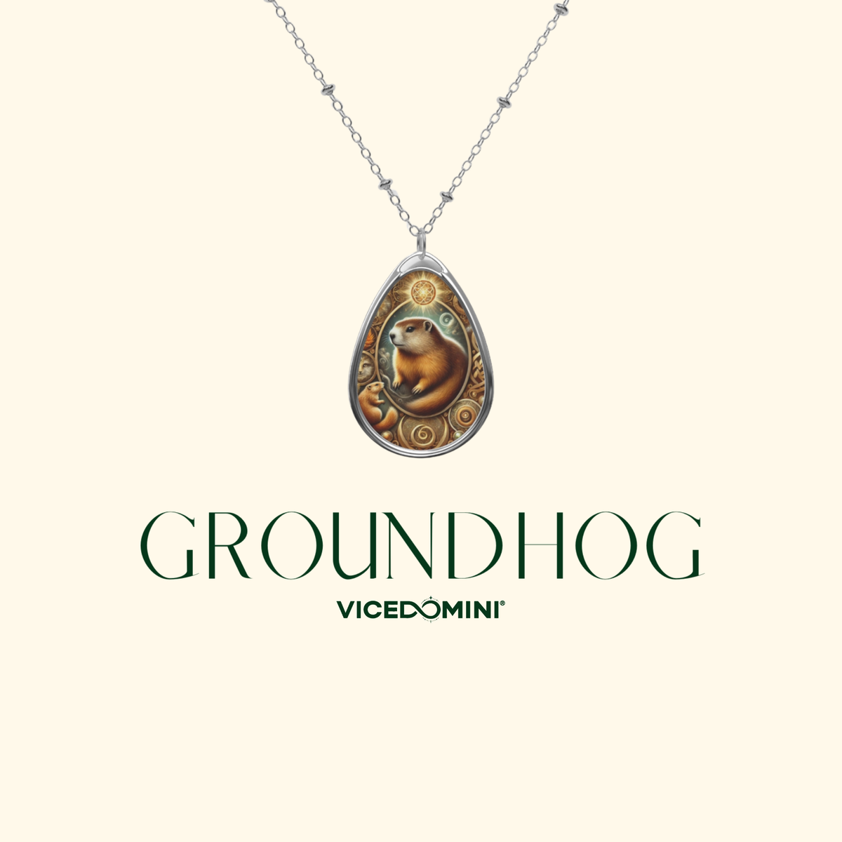 A teardrop-shaped pendant necklace featuring a groundhog illustration in warm brown and orange tones, surrounded by decorative gold and green motifs, suspended from a silver-toned chain. The pendant is centered on a light cream background with the text 'GROUNDHOG' and 'VICEDOMINI' below.