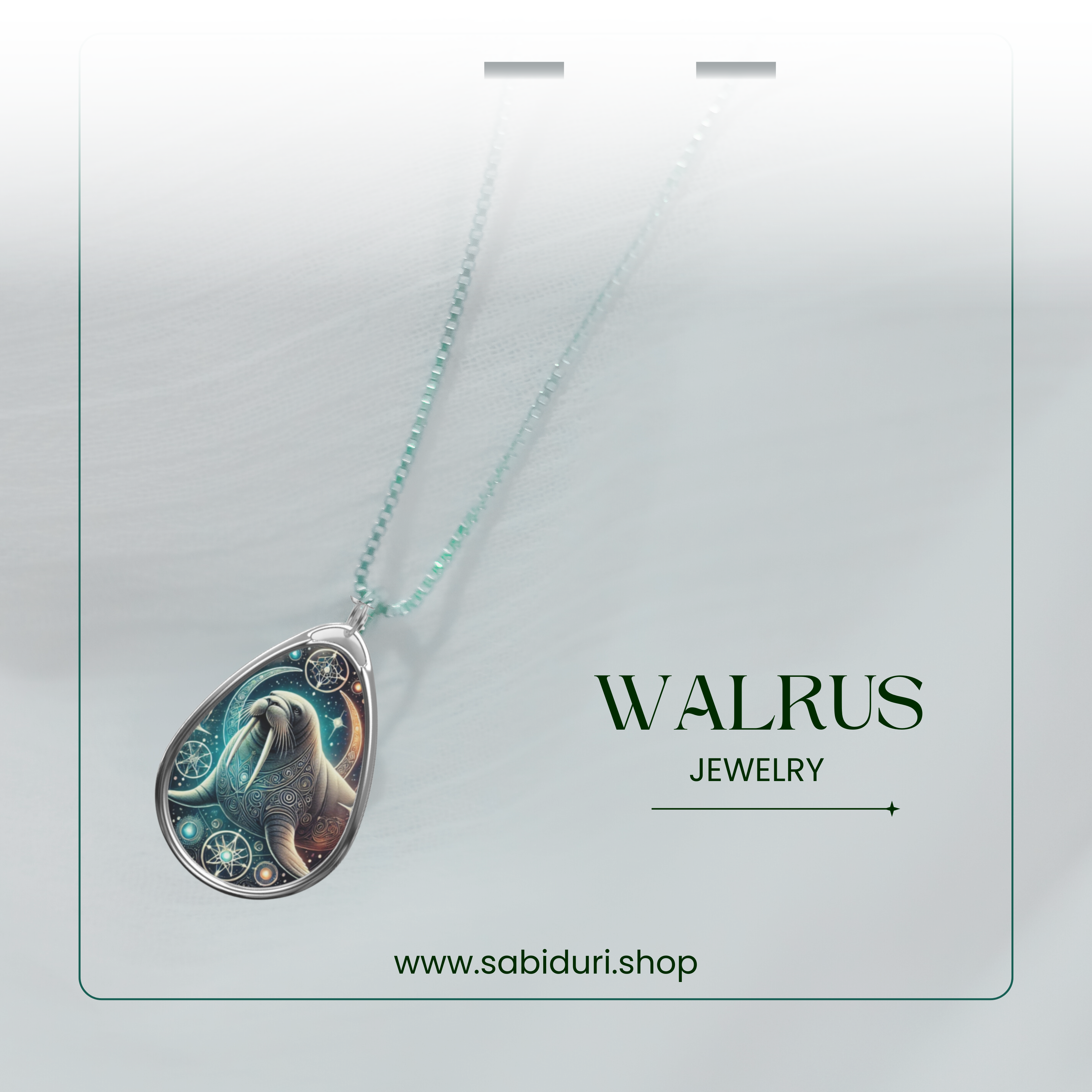 A refined product shot of the walrus necklace, elegantly draped over a soft, light-colored fabric with a subtle green-tinted chain. The pendant’s celestial walrus design shines under soft lighting, with the website 'www.sabiduri.shop' displayed below.