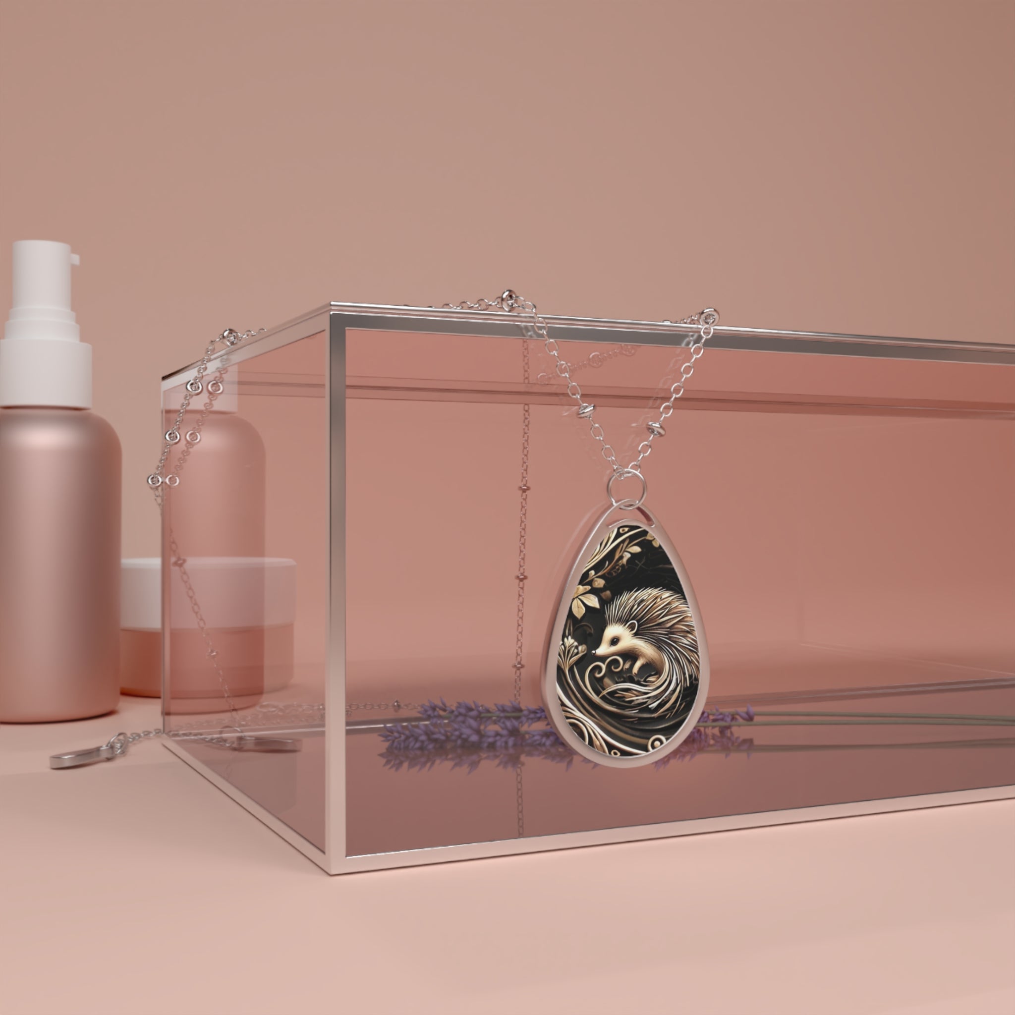 A teardrop-shaped necklace with a hedgehog pendant draped over the edge of a glass box. The background features soft, muted tones with a few skincare bottles and a lavender sprig beside the necklace, giving a minimalist and elegant aesthetic.