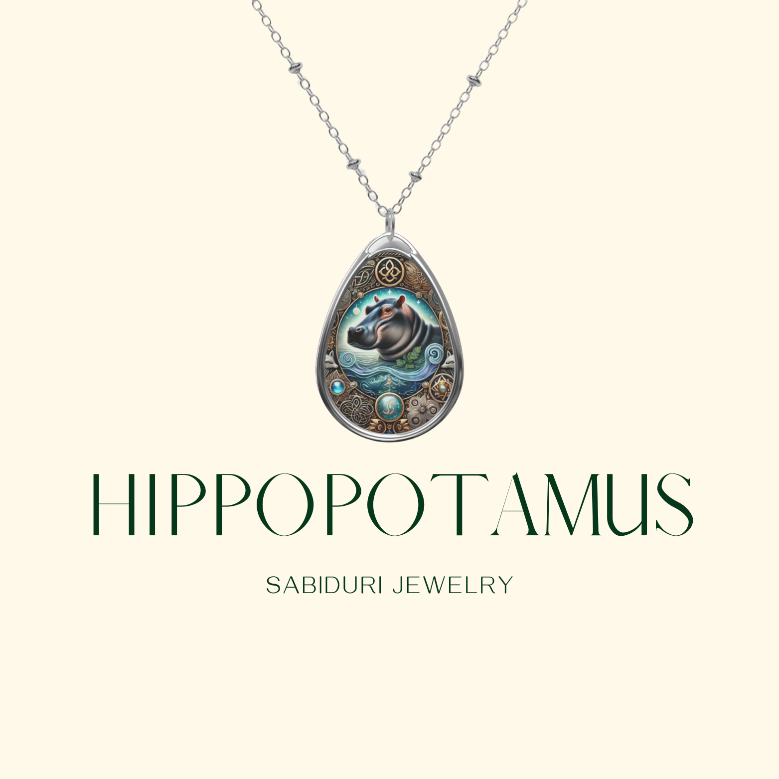 A teardrop-shaped silver pendant featuring an intricately designed hippopotamus surrounded by ornate, nature-inspired patterns. The necklace hangs gracefully against a cream background with "Hippopotamus" and "Sabiduri Jewelry" displayed in elegant green typography.