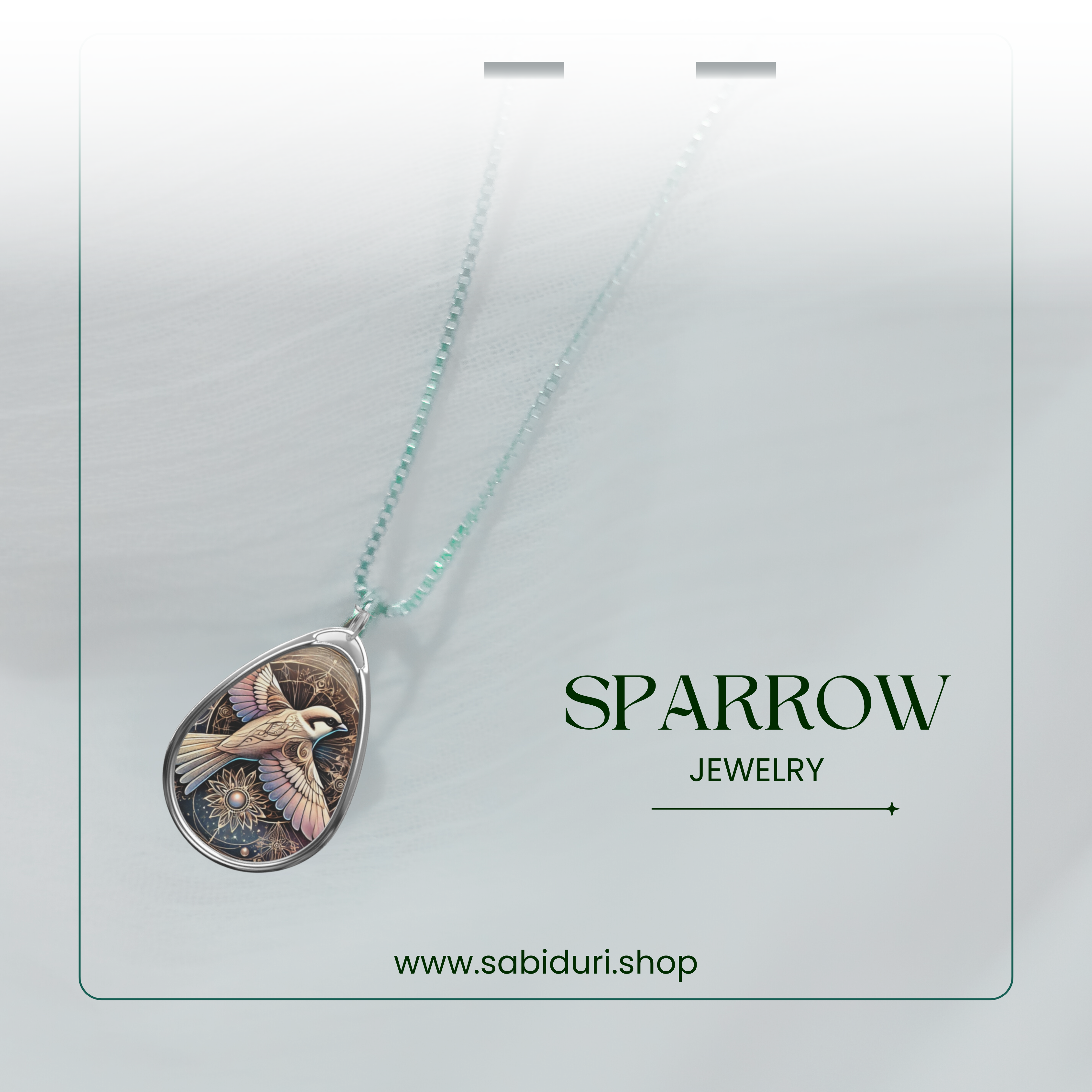 A silver-framed sparrow pendant with a harmonious blend of neutral tones and celestial motifs, suspended from a delicate chain against a softly blurred white fabric background. The text "SPARROW JEWELRY" and "www.sabiduri.shop" is present.