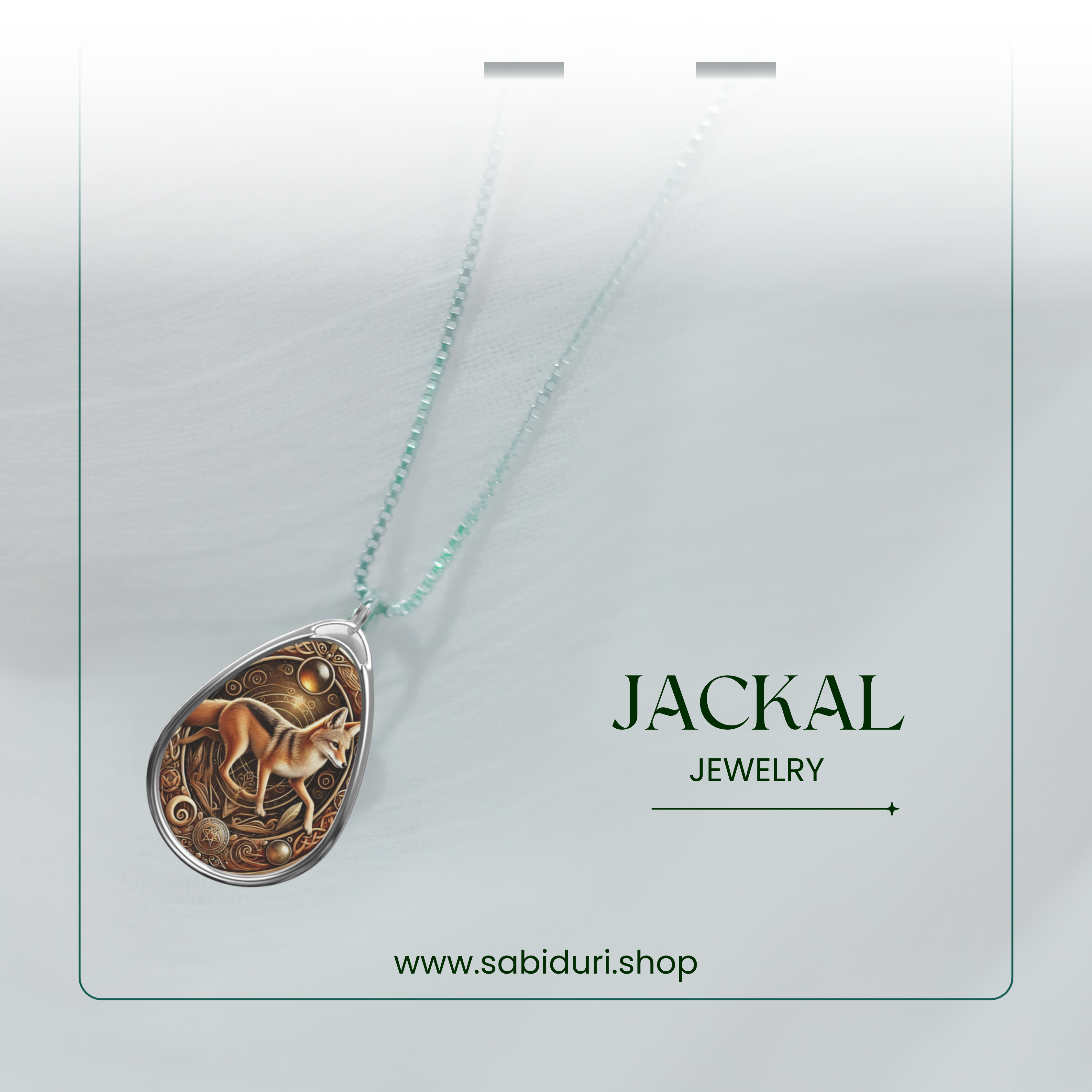 A silver chain necklace with a detailed jackal pendant, featuring intricate golden designs and celestial motifs. The pendant is set against a softly blurred white background with the text "Jackal Jewelry" and "www.sabiduri.shop."