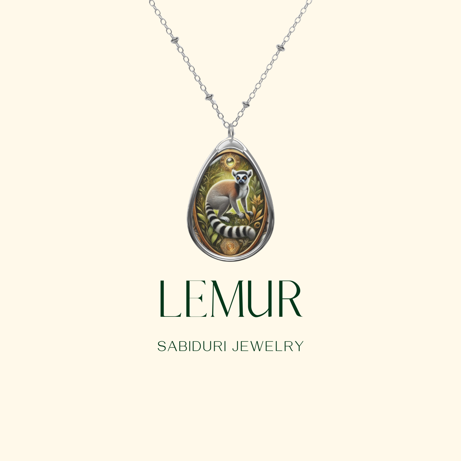 A silver teardrop pendant with a detailed depiction of a lemur in a lush jungle scene, suspended from a delicate silver chain. The background is a clean, cream tone with the text "LEMUR" and "SABIDURI JEWELRY" elegantly displayed.