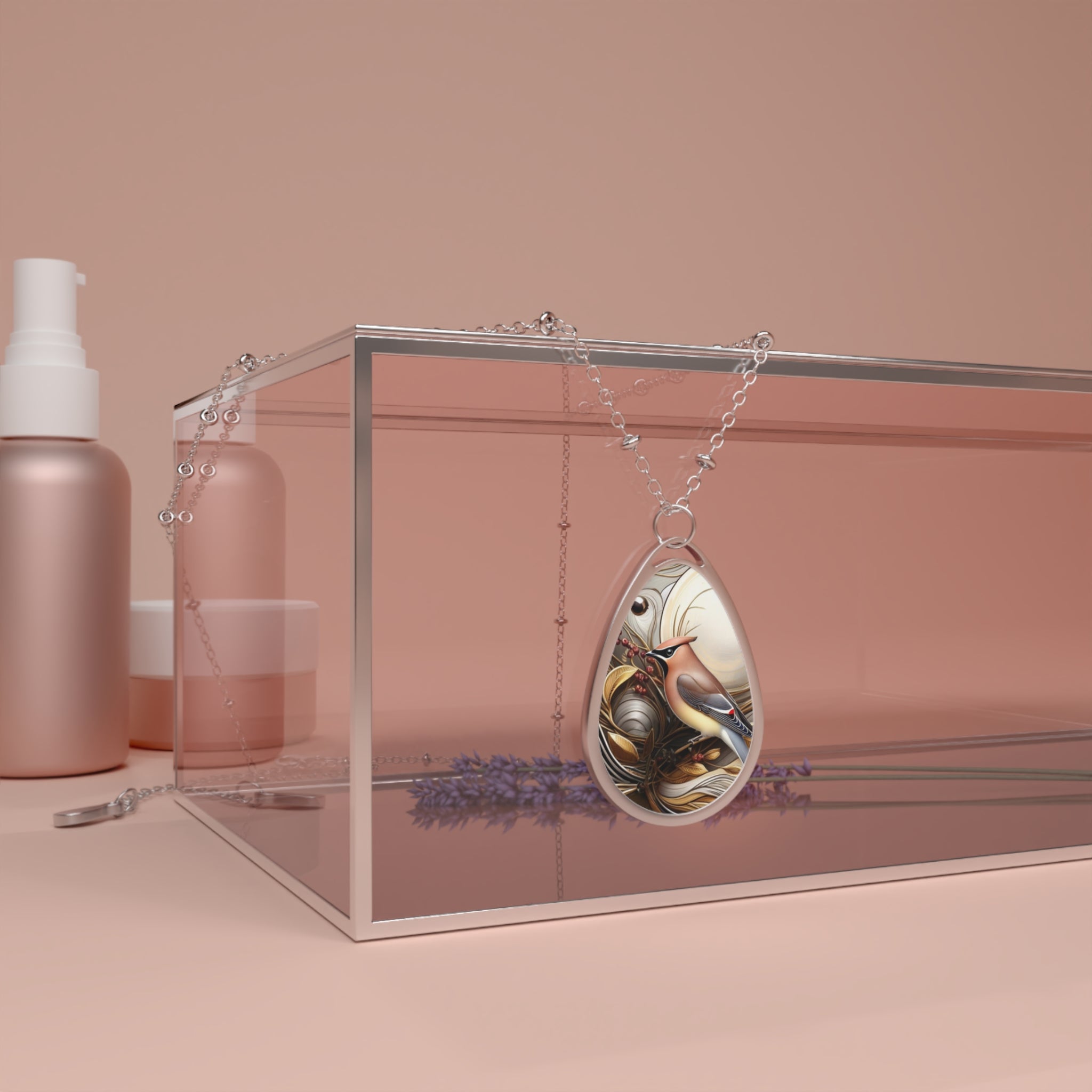 The Cedar Waxwing Spirit Animal necklace draped over a transparent glass box with a soft pink tint. The background includes matching pink beauty products, creating a cohesive and modern aesthetic. The pendant's detailed bird design is clearly visible, making the necklace the focal point of the image.