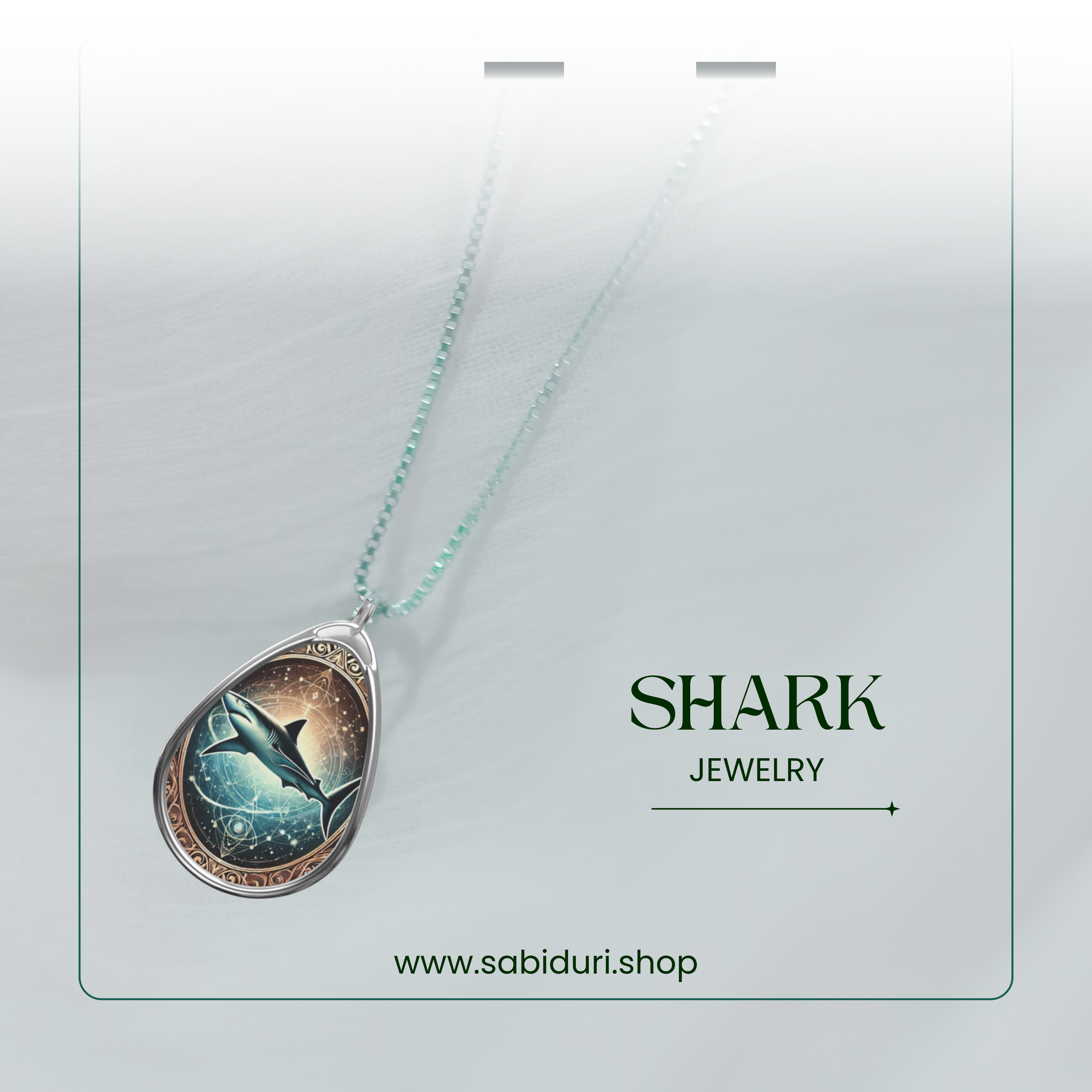 A dreamy close-up of a silver shark pendant necklace draped over a soft, white fabric. The pendant has a celestial design with a shark swimming in a mystical ocean, adorned with glowing star-like details. "SHARK JEWELRY" and "www.sabiduri.shop" are displayed in the bottom corners.